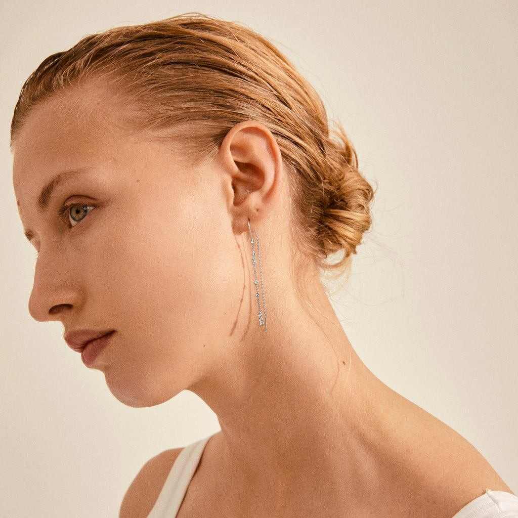 Close-up of a woman wearing Pilgrim's KAMARI silver-plated crystal chain earrings, showcasing their elegance and discreet charm for life’s special moments.