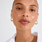 EILEEN gold-plated twirl hoop earrings on model with medium-brown skin, visible nose ring, and white shirt, showcasing playful, whimsical design inspired by summer's boho energy.