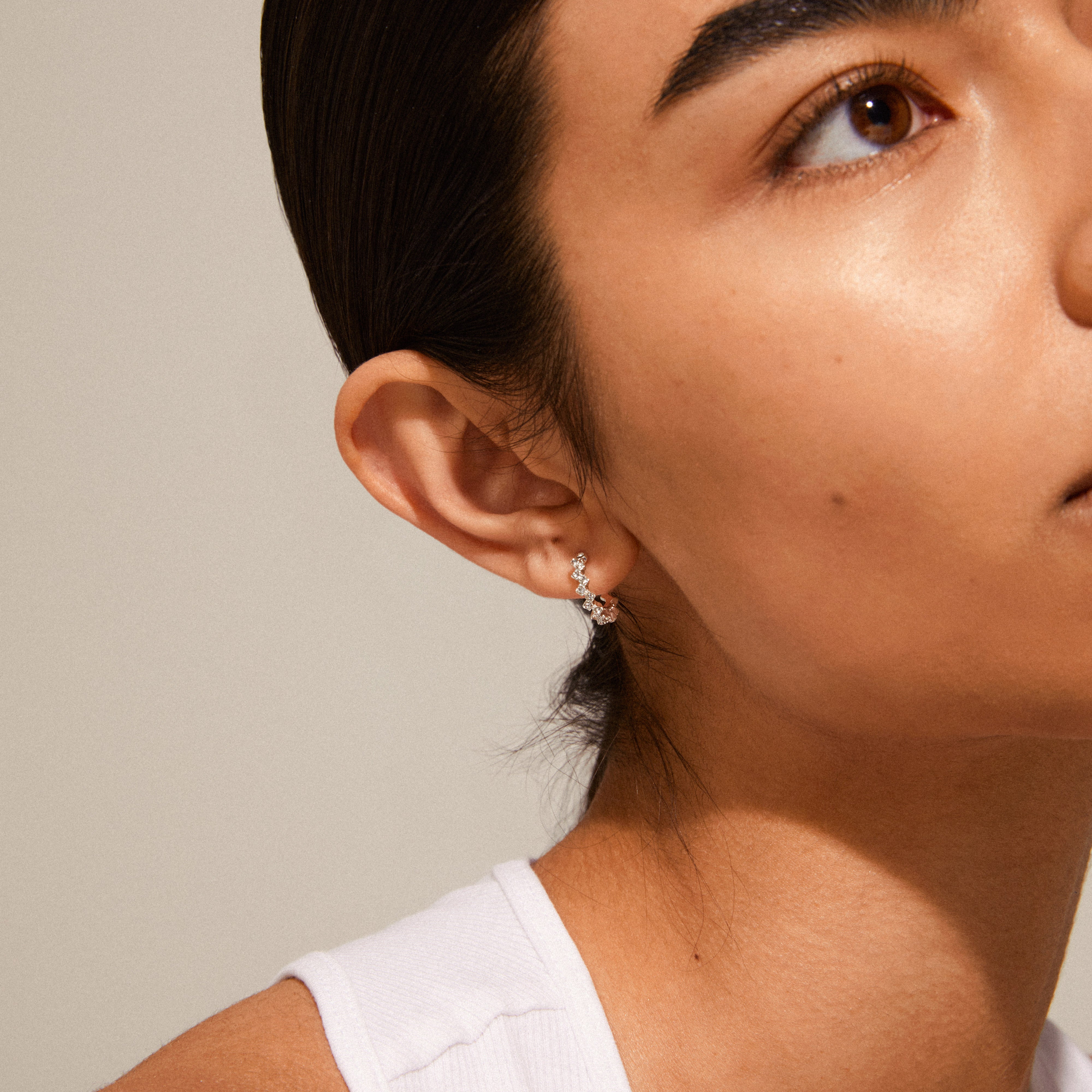Close-up of a woman's face wearing ESTER crystal hoop earrings, silver-plated, showcasing their angular design and sparkling Preciosa crystals.