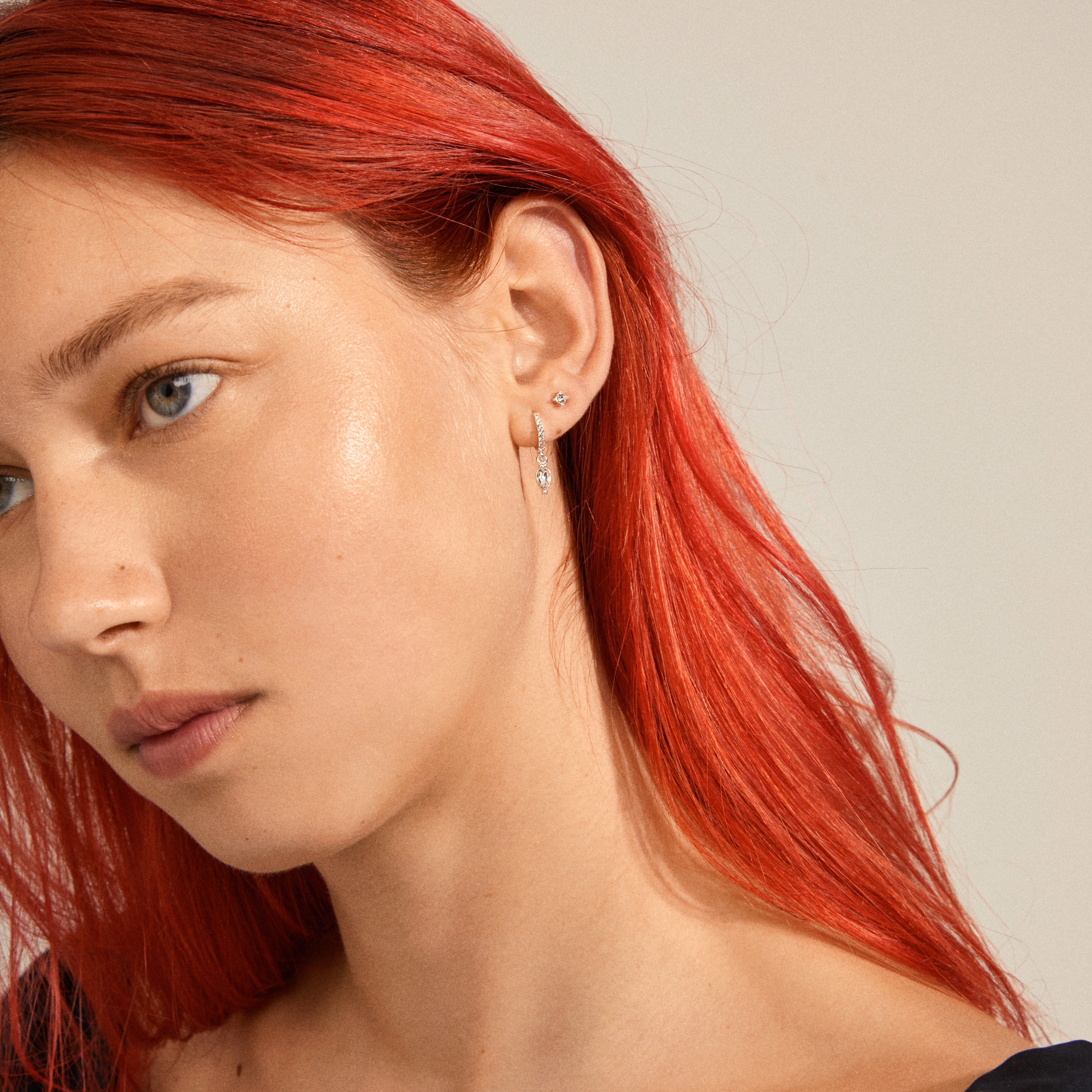 ELZA crystal earrings 2-in-1 set silver-plated, featuring small ear studs and huggie hoops with teardrop pendants and Preciosa crystals, worn by a red-haired woman.