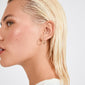 Profile view of a person wearing EANNA medium hoops gold-plated by Pilgrim, showcasing the sleek design and smooth, dewy skin.