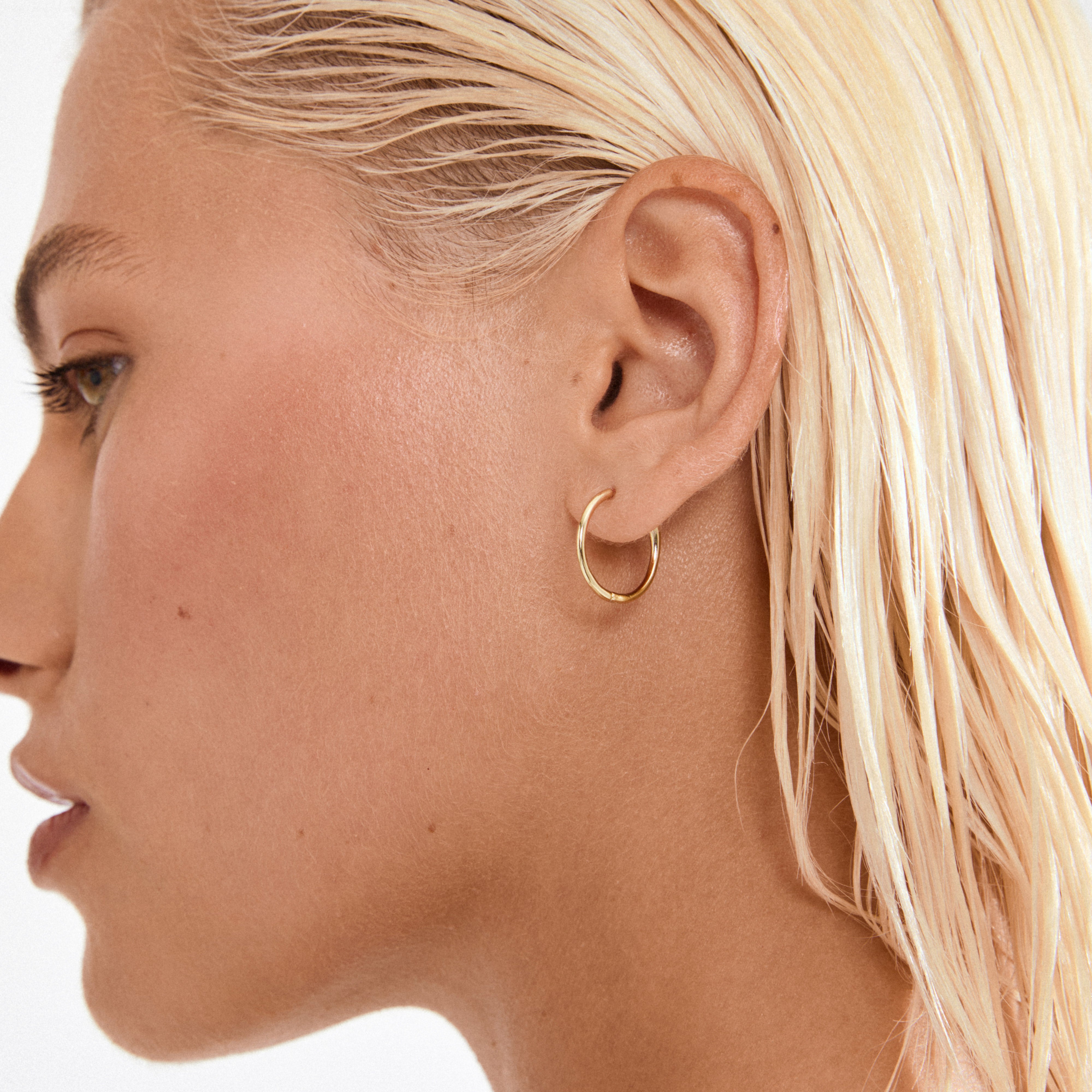 Side profile showing EANNA medium gold-plated hoop earring by Pilgrim, featuring a simple design with a smart click lock.