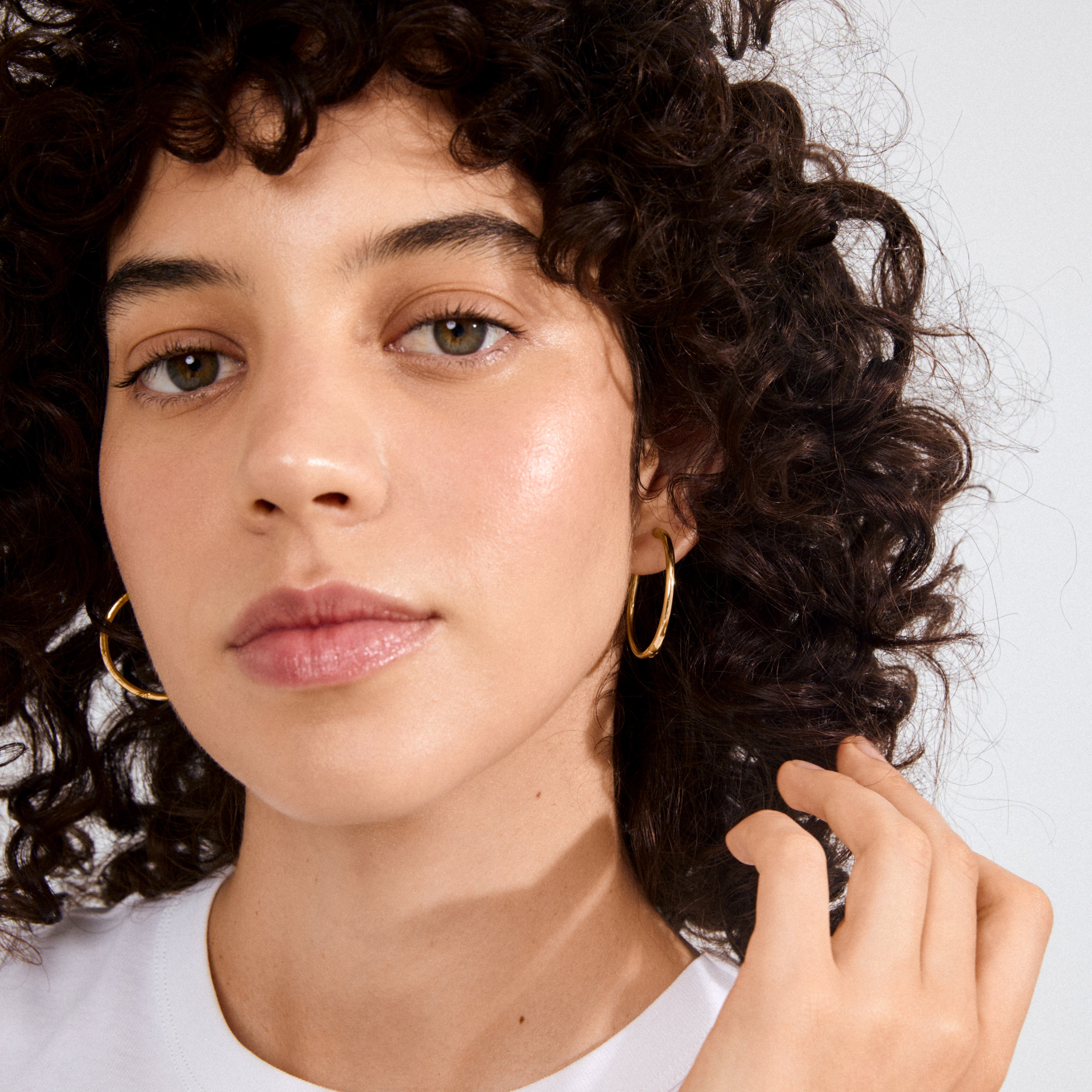 Person wearing EANNA maxi hoops gold-plated by Pilgrim, showcasing elegant, recycled gold-plated hoops with an easy click lock, paired with simple gold earrings.