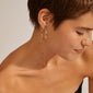 EANNA maxi hoops gold-plated adorn a woman's ear, showcasing their elegant design and easy-to-use click lock mechanism. Perfect for versatile styling.