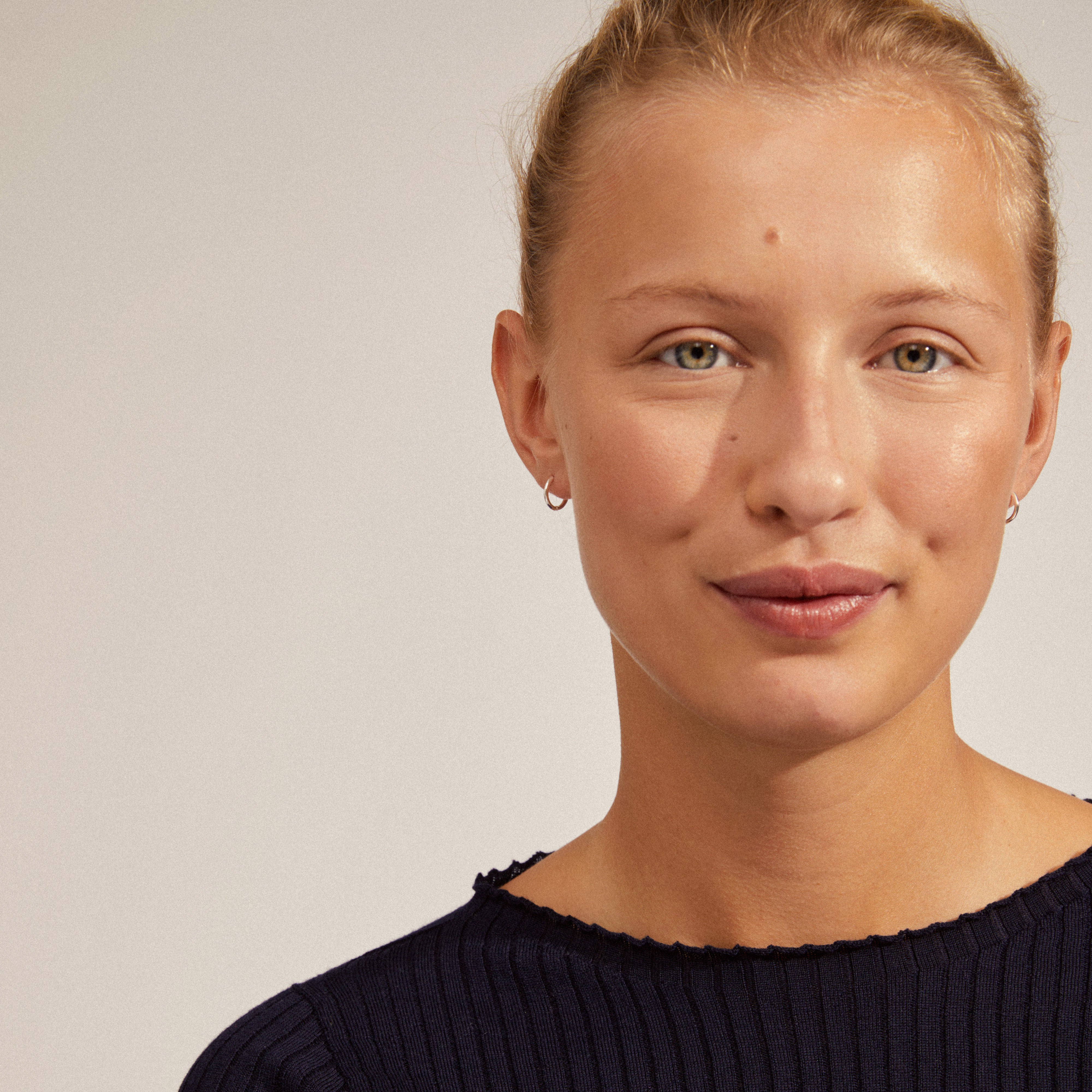 EANNA silver-plated small hoops worn by a woman with blonde hair and a black shirt, showcasing their elegant and versatile design.