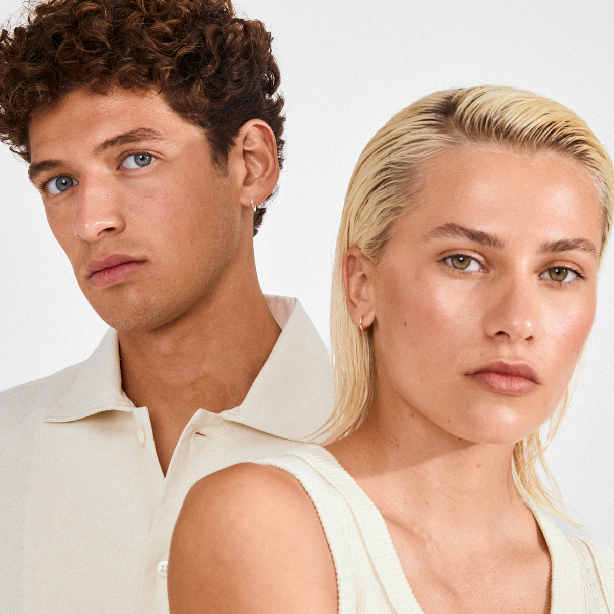 Two young adults wearing EANNA small hoops silver-plated earrings. The minimal design complements their casual tops, embodying Pilgrim's timeless, trendy style.