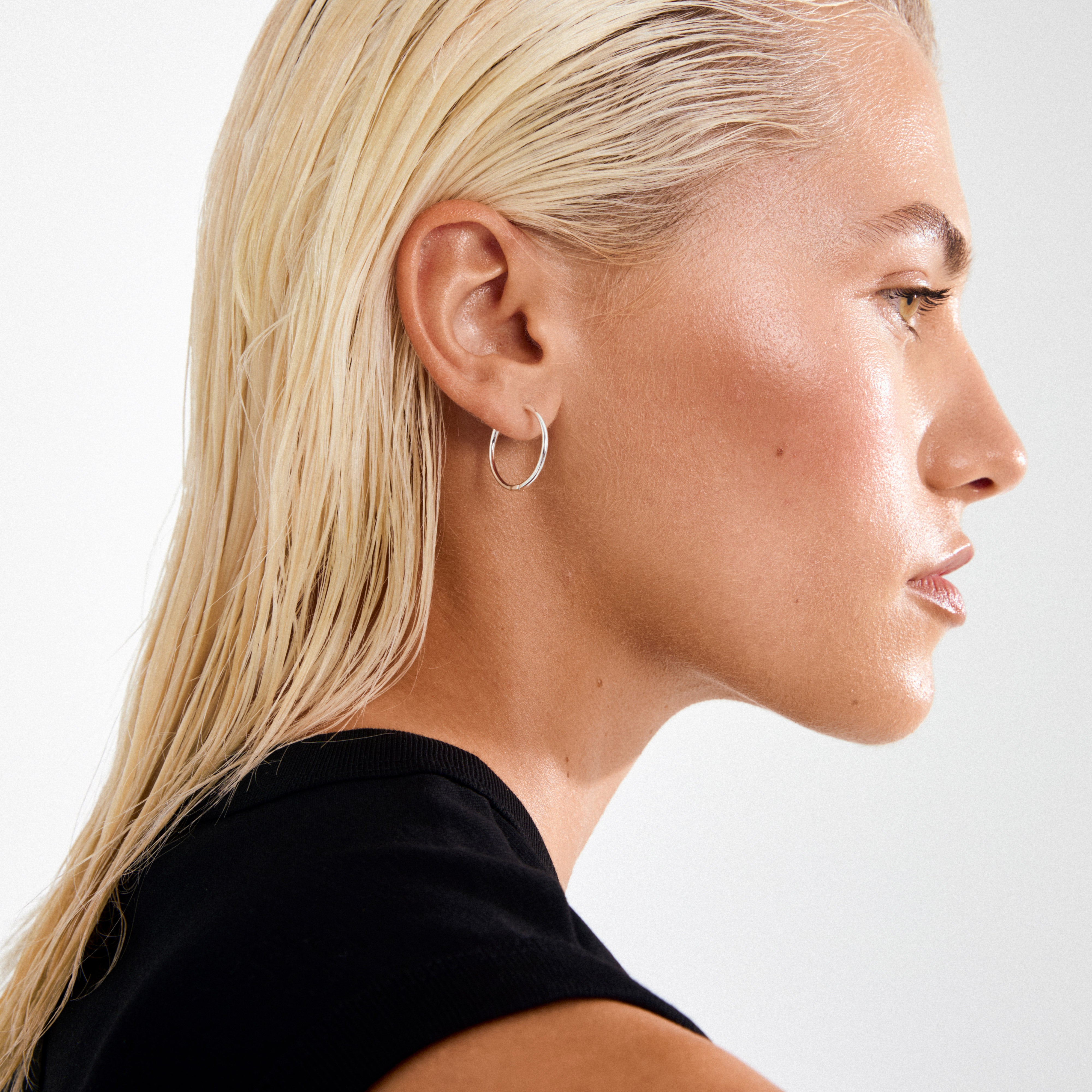 Profile view featuring EANNA large hoops silver-plated; sleek, stylish, and crafted from 99% recycled material, embodying timeless elegance with a trendy, wide silhouette.
