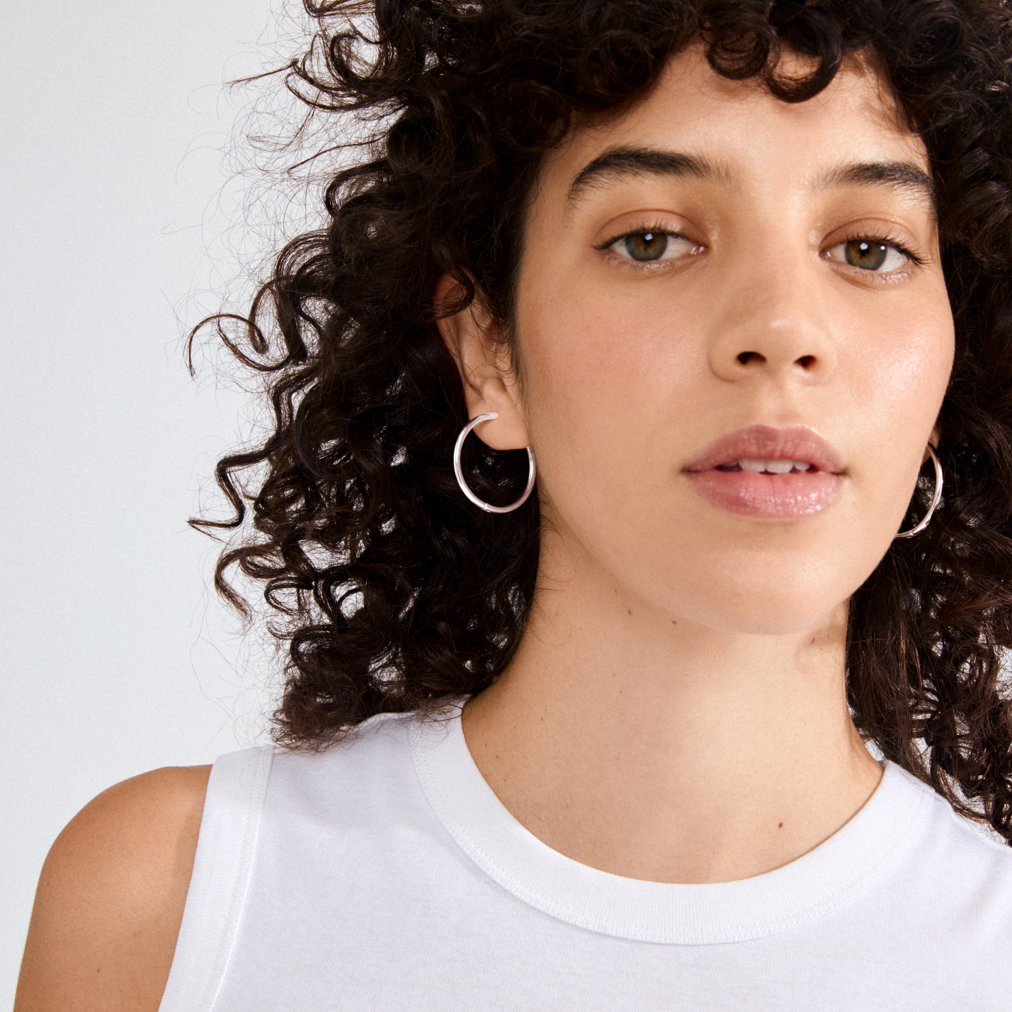 Young person wearing EANNA maxi hoops silver-plated earrings, showcasing their timeless, elegant design. Perfect for versatile styling with various outfits.