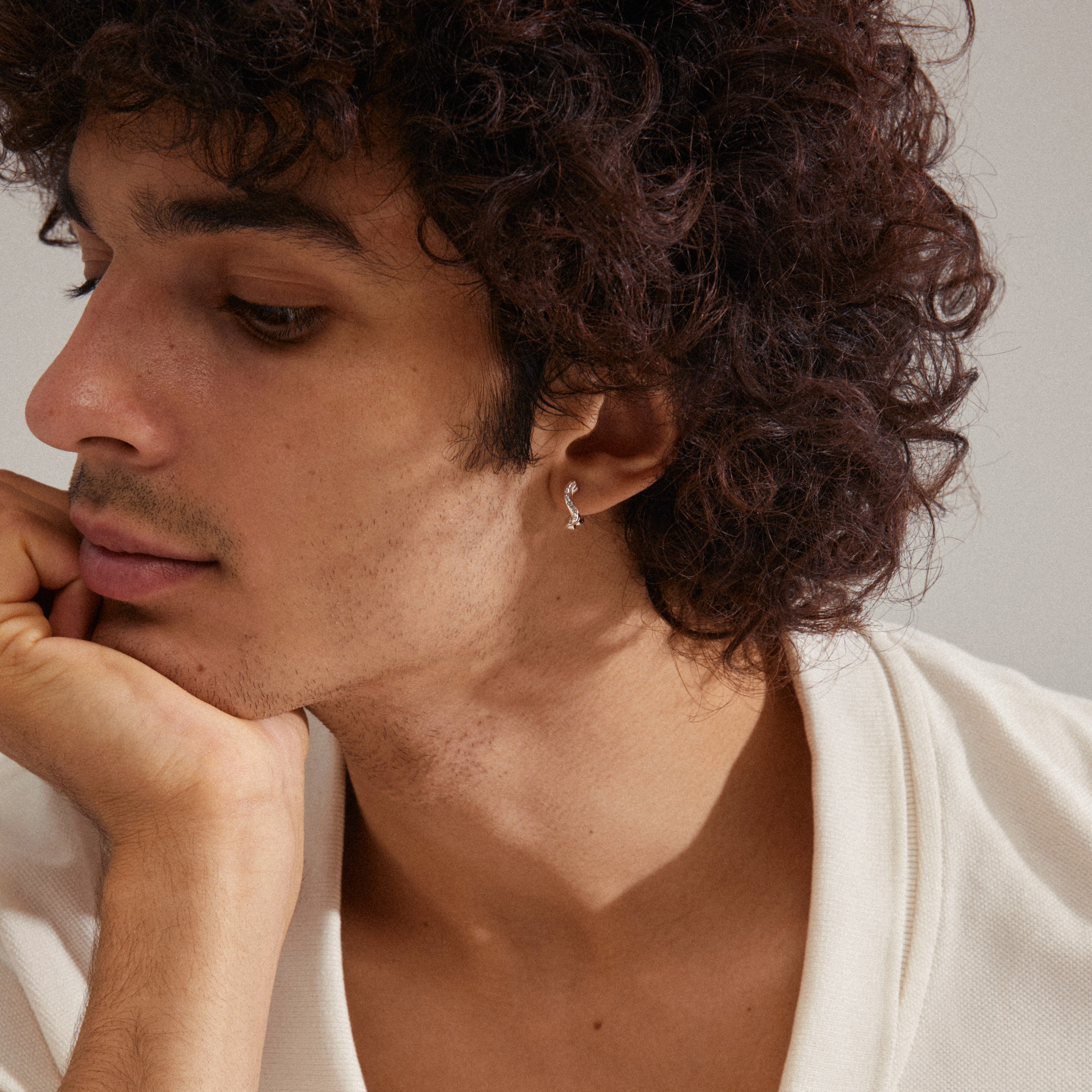 Close-up of a man wearing EVRA organic shaped crystal hoops, silver-plated earrings with sparkling Preciosa crystals, capturing a blend of elegance and handcrafted detail.