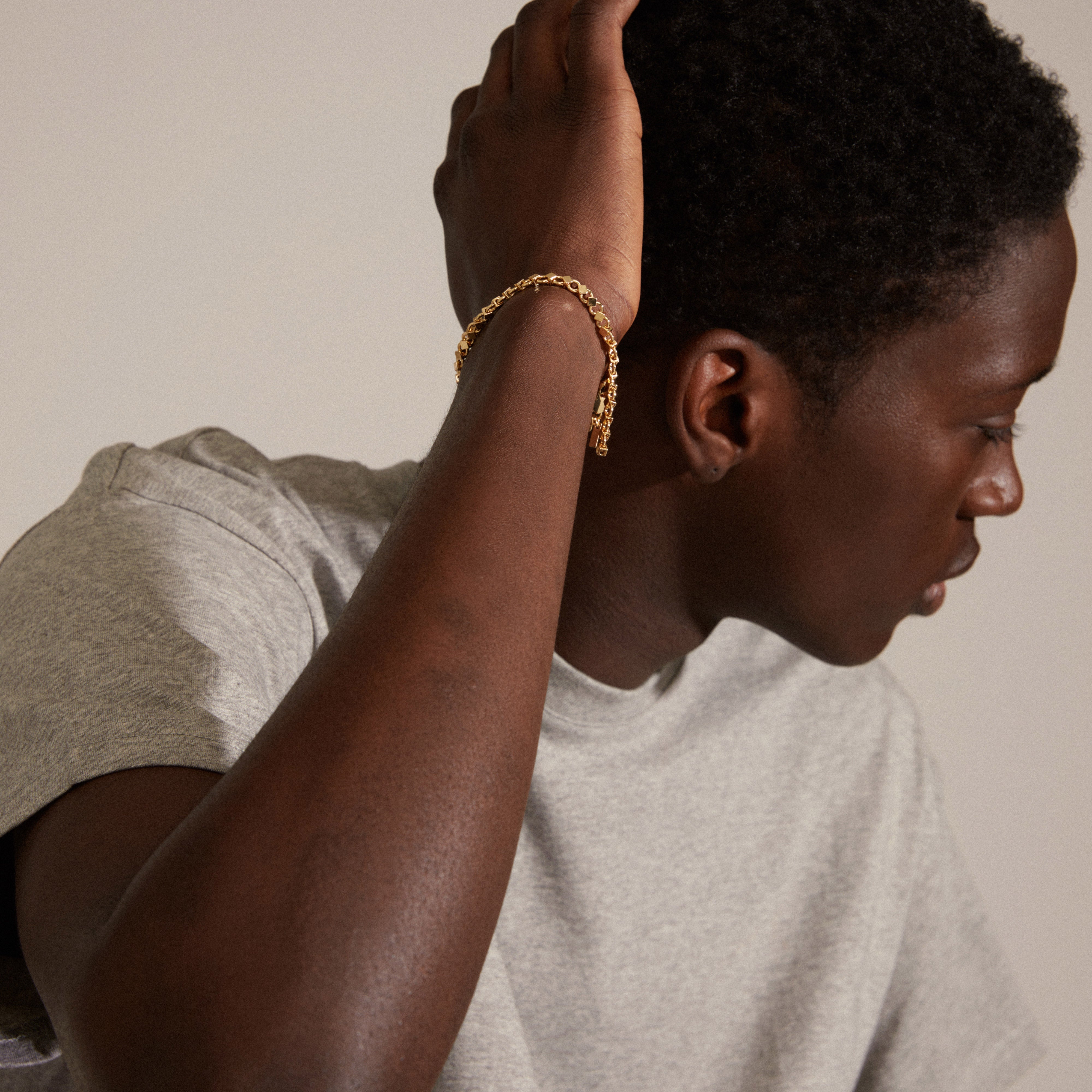 DESIREE gold-plated bracelet showcased on a man's wrist, featuring a unique chain design with cubes and round links from Pilgrim's handcrafted collection.