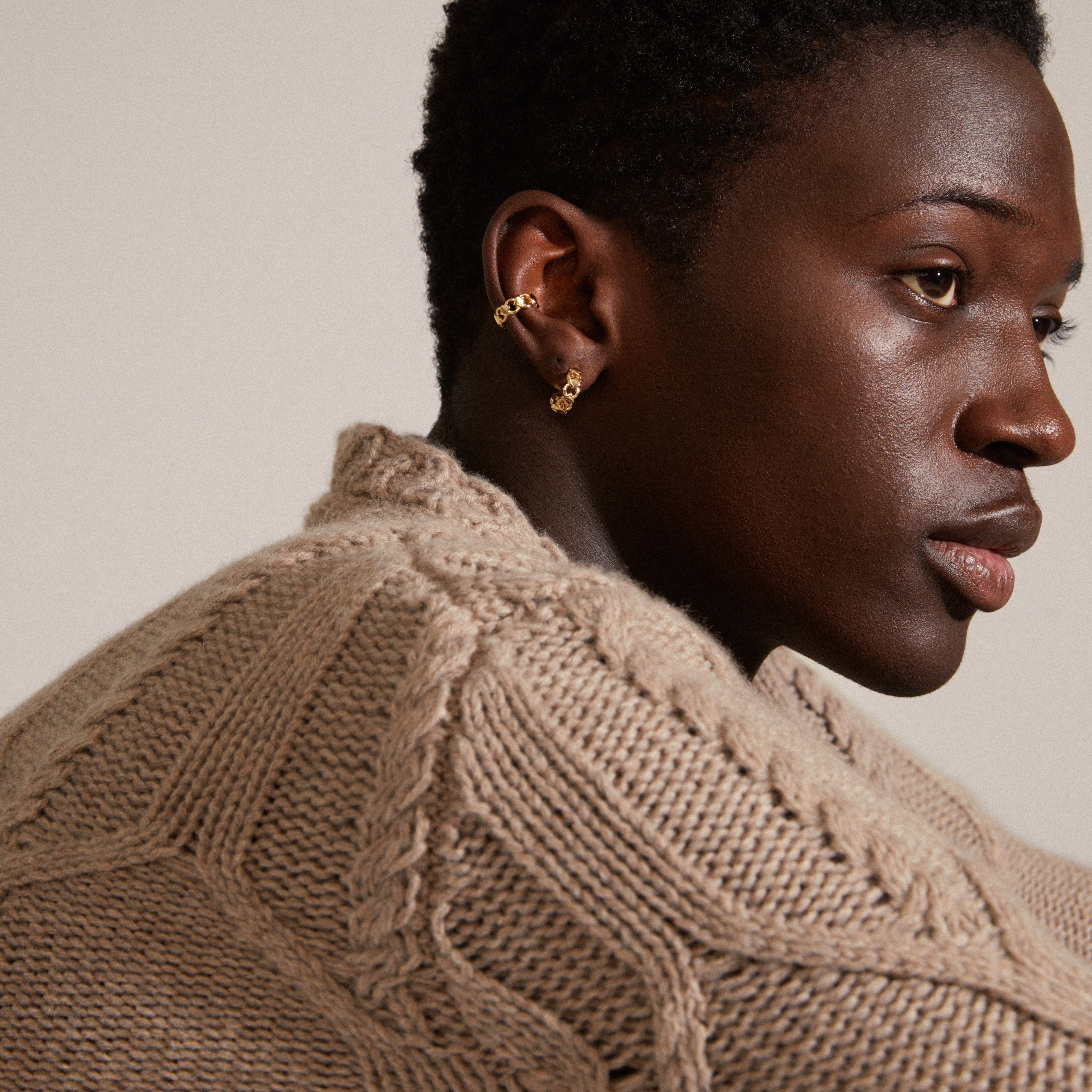 Woman wearing DESIREE gold-plated hoop and cuff earrings by Pilgrim, showcasing a unique chain design with cubes and round links.