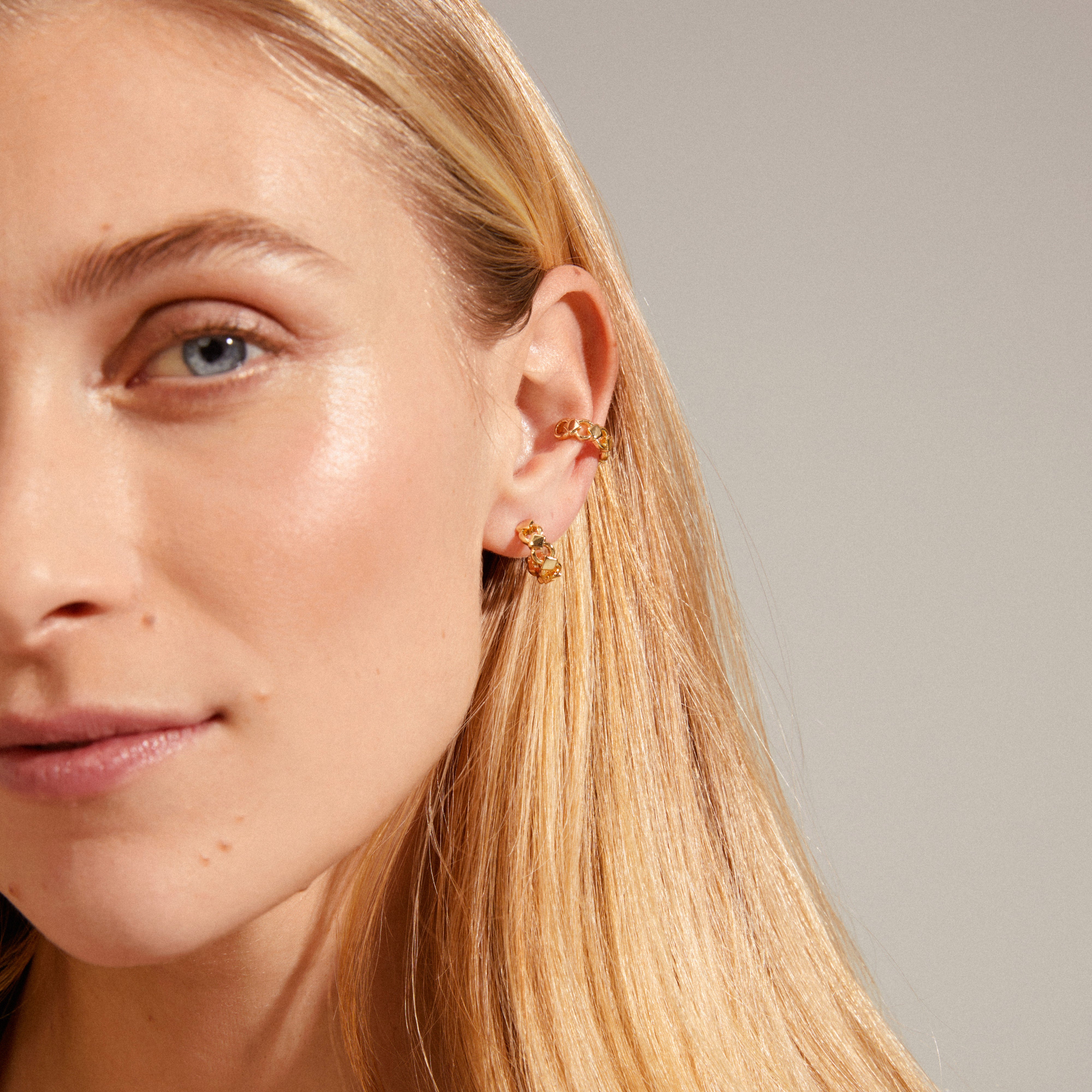 DESIREE gold-plated hoop and cuff earrings showcased on a woman's ear, featuring a unique chain design with cubes and round links for a trendy look.