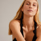 Woman showcasing Pilgrim's DESIREE gold-plated huggie hoops and ear cuff, featuring a unique chain design with cubic and round links, emphasizing sustainable, stylish fashion.