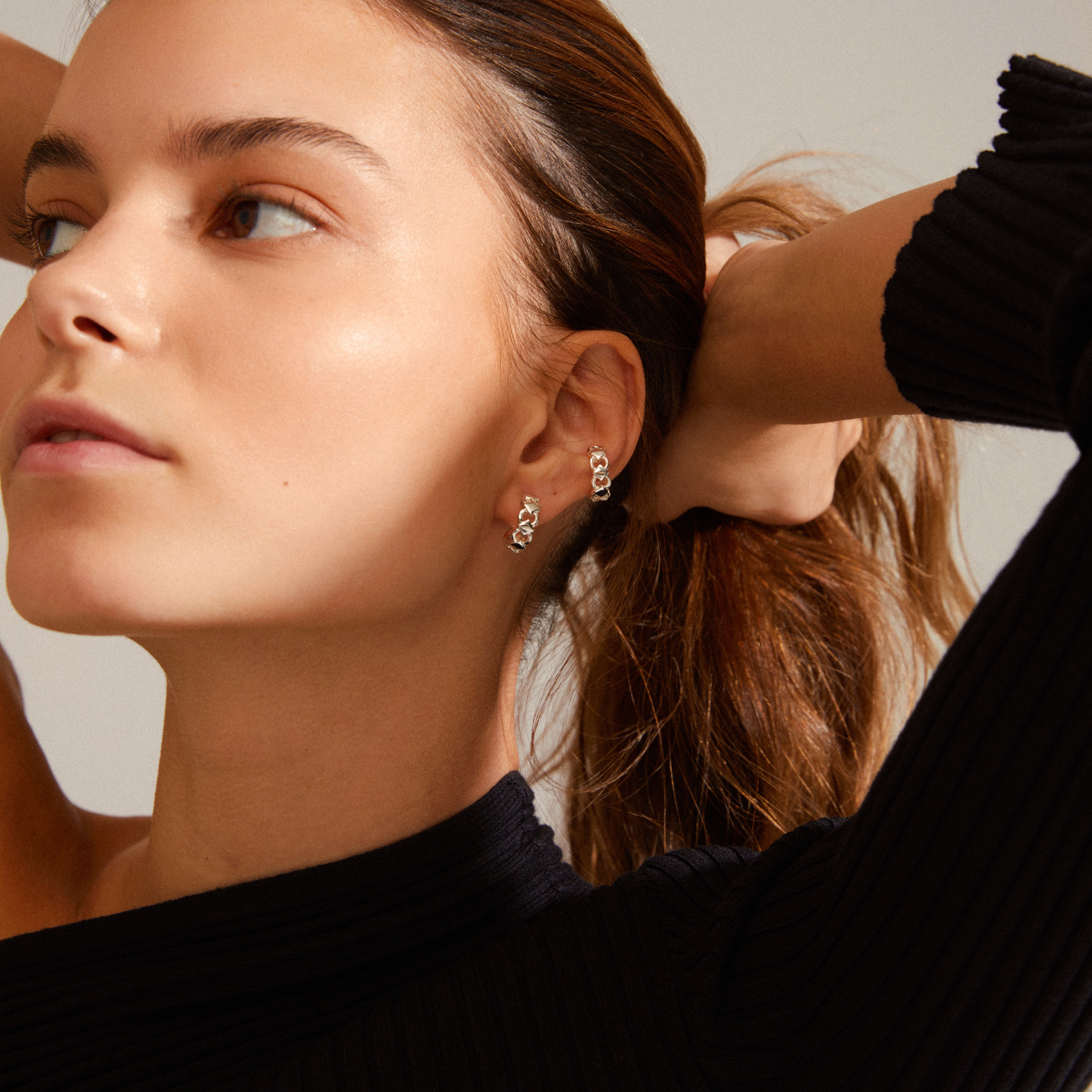 DESIREE hoop and cuff earrings, silver-plated, featuring a chain design with cubes and round links, worn by a woman with pulled-back hair.