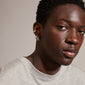 DESIREE silver-plated huggie hoops and ear cuffs with unique chain design, featuring cubes and round links. Modeled by a man, showcasing trendy style.