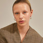 Close-up of a woman wearing RUE recycled gold-plated hoops, showcasing their sparkling glass stones and elegant design. Perfect for adding glam to any outfit.