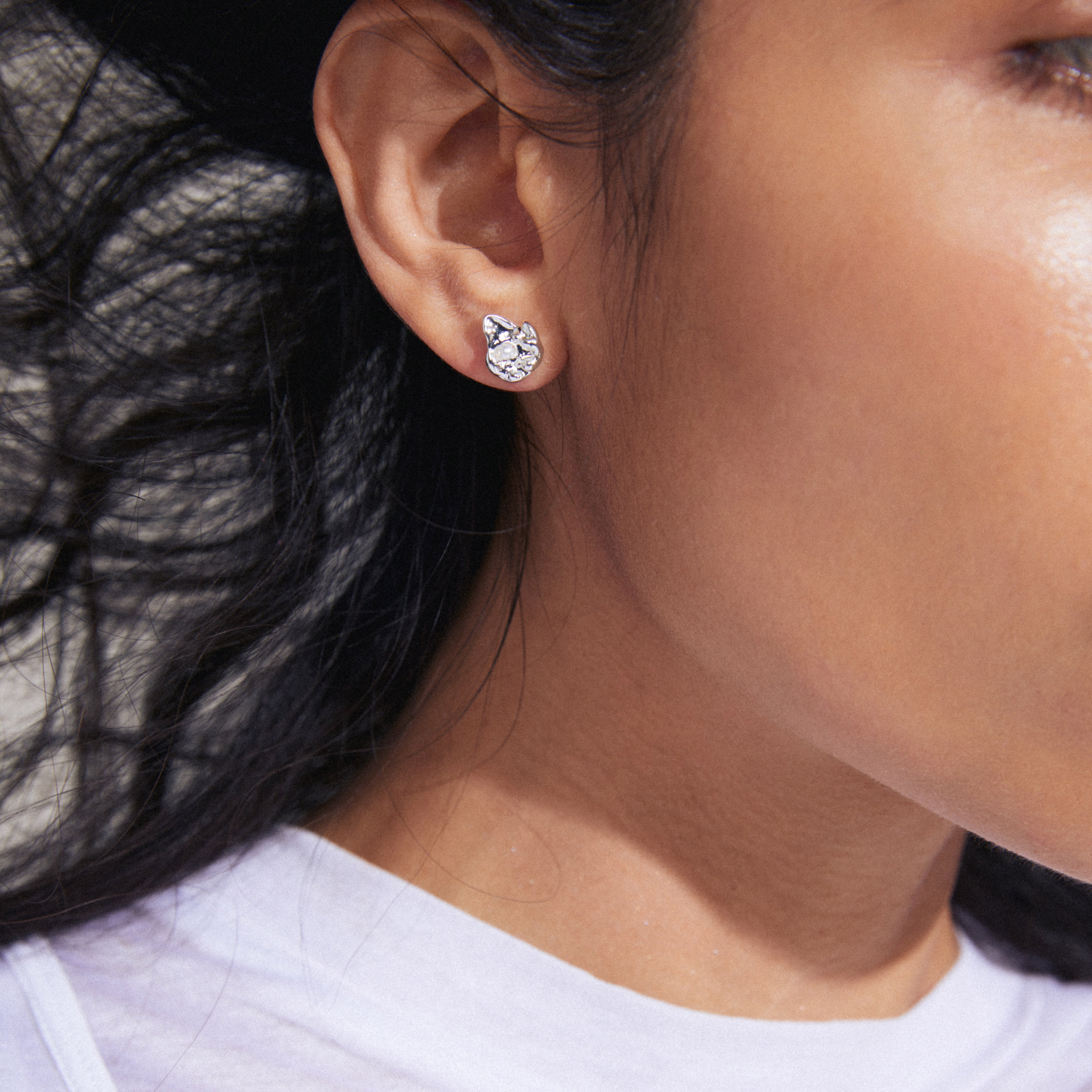 INAYA earrings silver-plated, close-up view. Features small abstract seashell studs with a central white glass bead, showcasing Pilgrim's detailed craftsmanship.