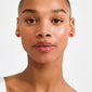 Young woman wearing SIGRUN earrings gold-plated, featuring small red enamel bow studs, showcasing Pilgrim's trendsetting, playful design with a minimalist touch.