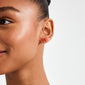 Close-up of a person wearing SIGRUN gold-plated earrings by Pilgrim, featuring small red enamel bows, perfect for adding a trendy touch to minimalist styles.