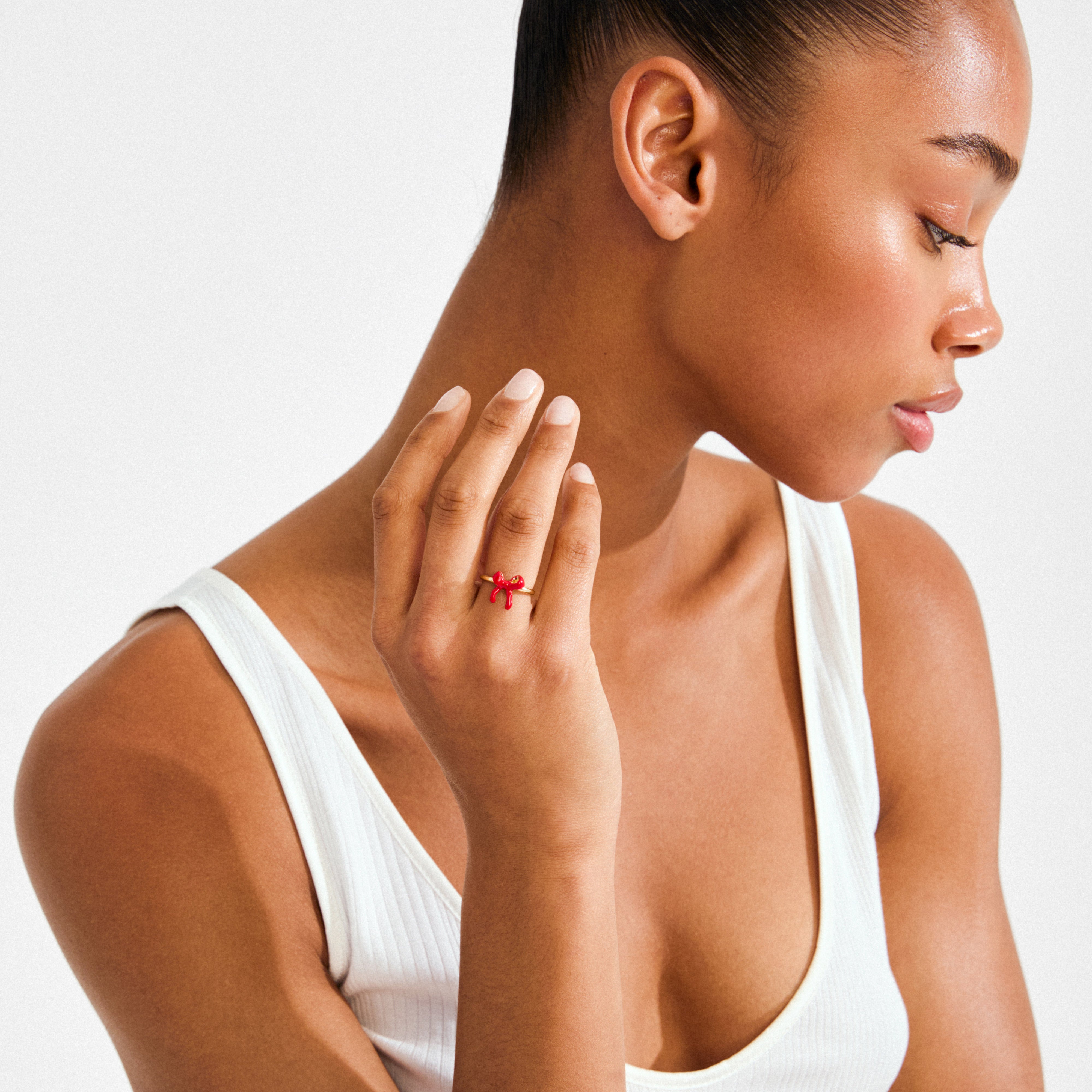 Young woman wearing the SIGRUN gold-plated ring by Pilgrim, featuring a small red bow, symbolizing personal dreams and elegance. Perfect for a trendy, meaningful look.