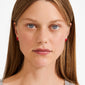 Young woman wearing SIGRUN earrings, silver-plated red enamel bows, showcasing Pilgrim’s playful, trendsetting style. Perfect for minimalist or preppy looks.