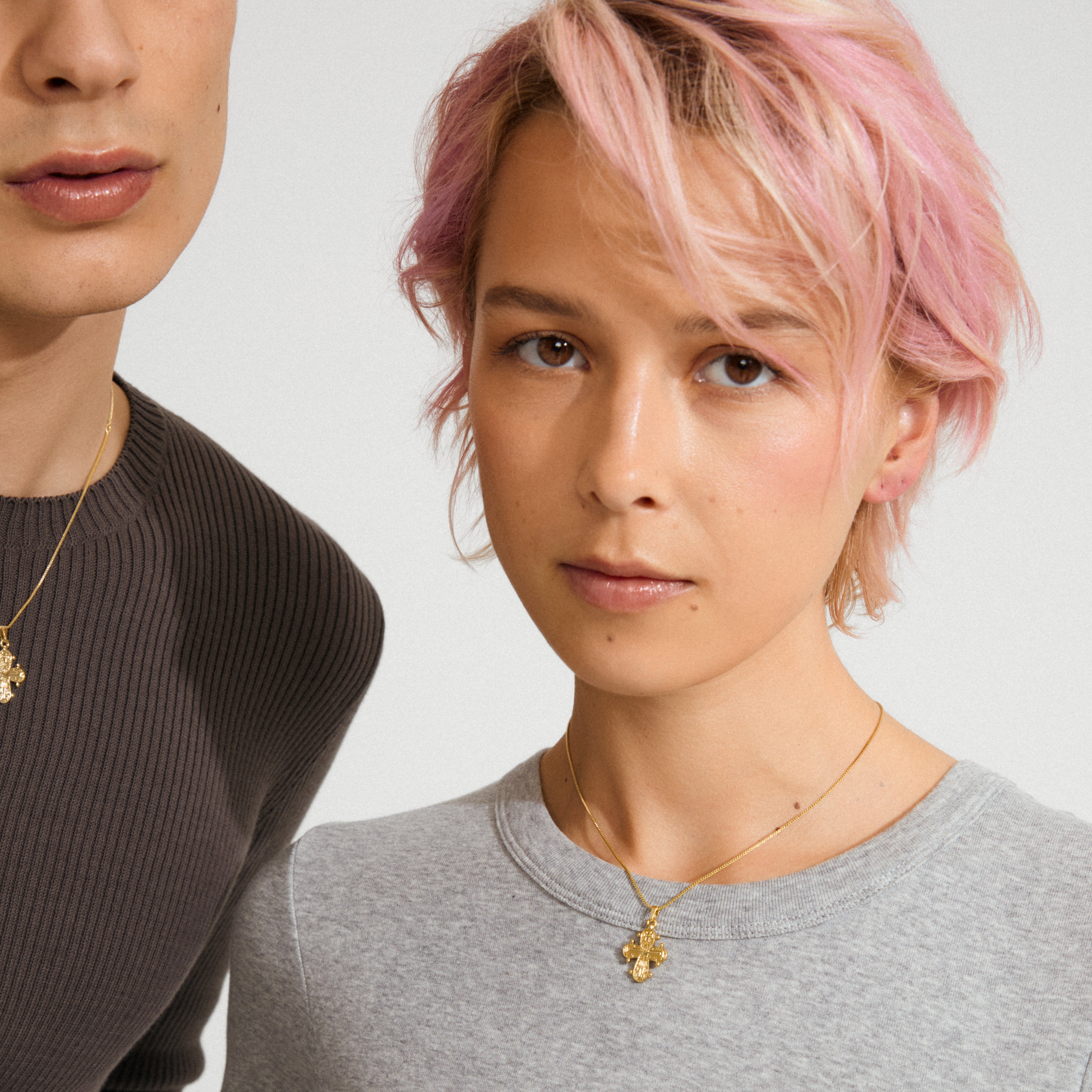Two people wearing the DAGMAR pendant necklace, gold-plated with a cross, showcasing Pilgrim's elegant, timeless design perfect for layering and personal style.