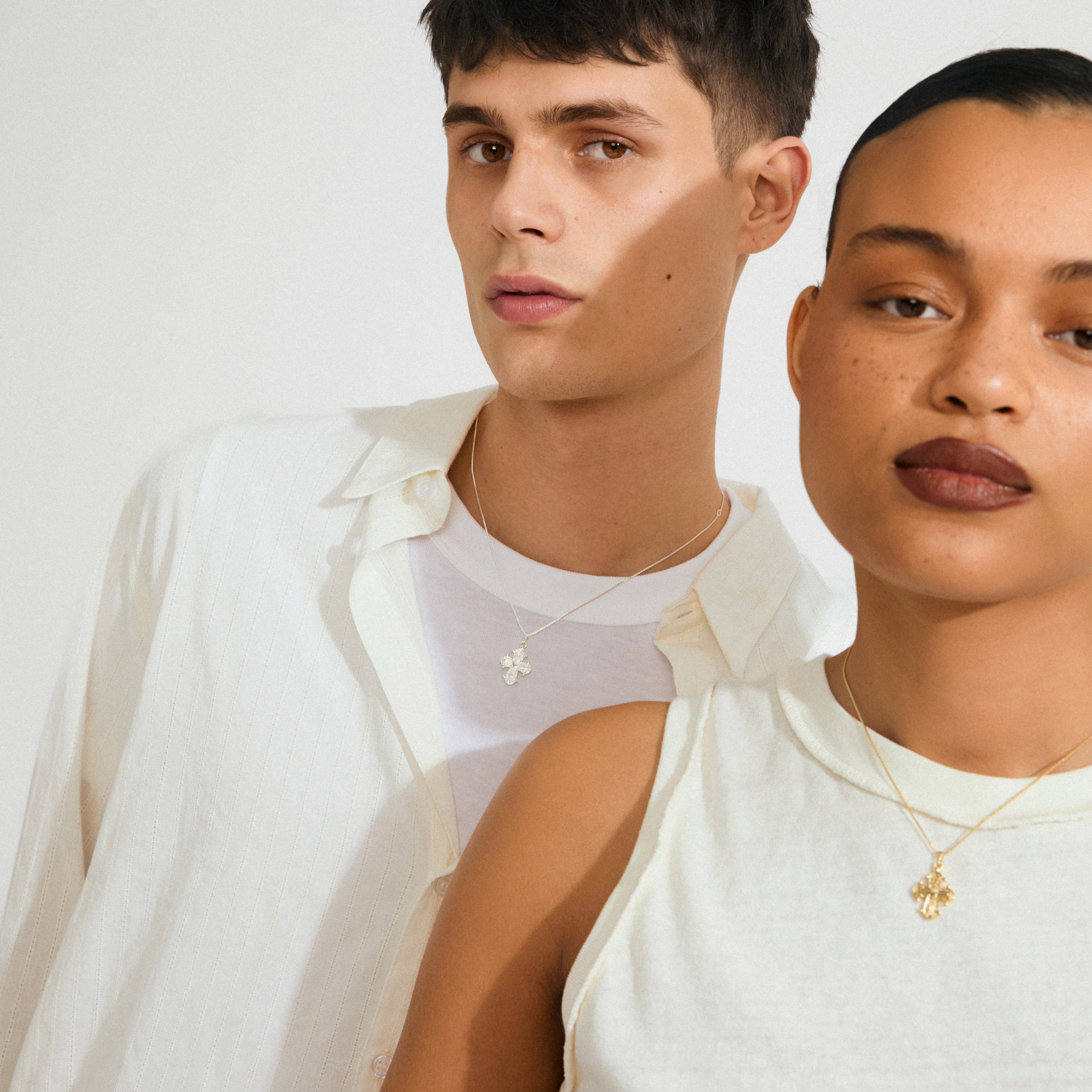 Two models showcase the DAGMAR pendant necklace gold-plated, featuring delicate floral-style cross pendants, highlighting Pilgrim's blend of timeless Danish elegance and modern style.