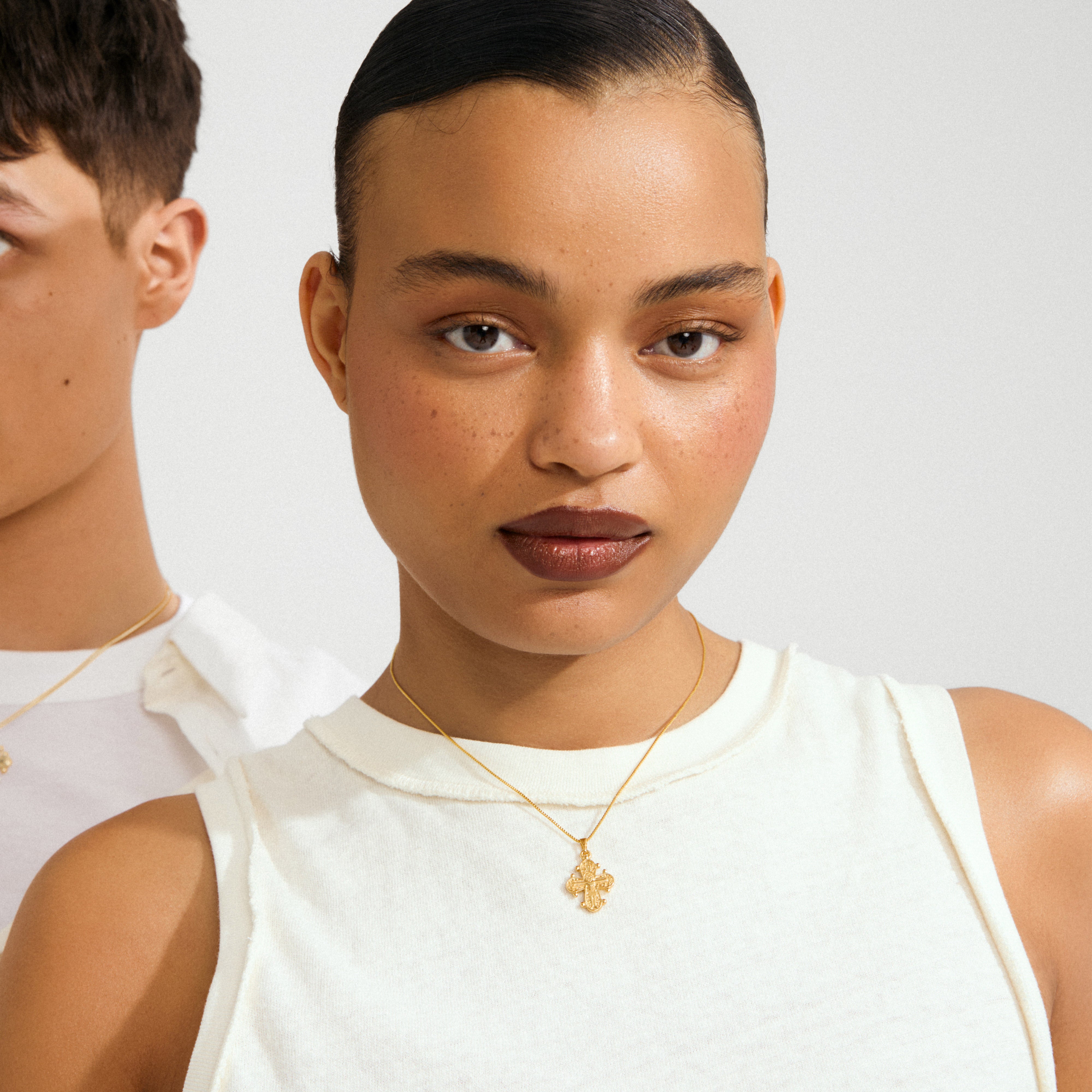 Young woman wearing the gold-plated DAGMAR pendant necklace, featuring a delicate cross on a thin chain, embodying Pilgrim's timeless Scandinavian elegance and craftsmanship.