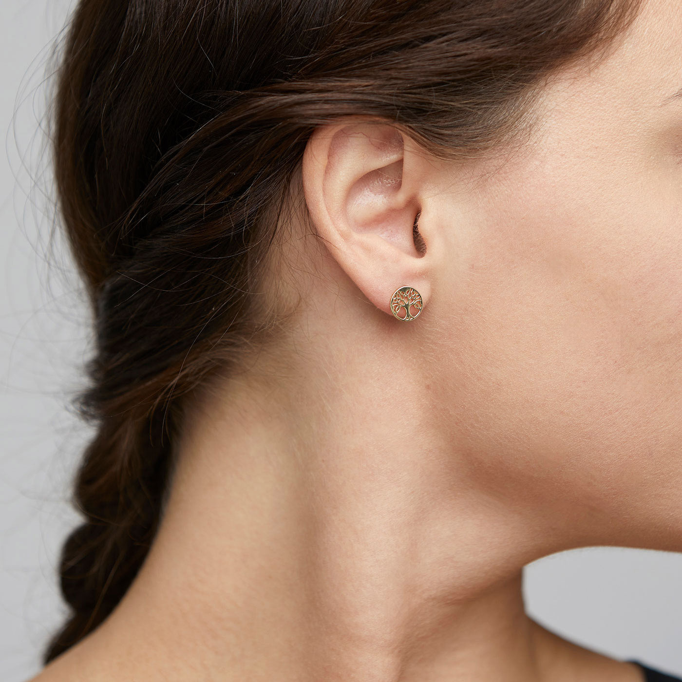 Close-up of a woman's ear showcasing Pilgrim's GEORGINA gold-plated ear studs, symbolizing the Tree of Life, highlighting elegance and personal growth.