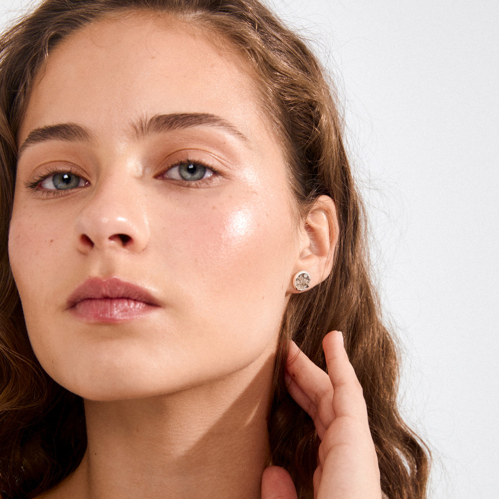 Young woman wearing JOSEFINE earrings, featuring silver-plated, textured crystal studs, blending edgy elegance with a nature-inspired design.