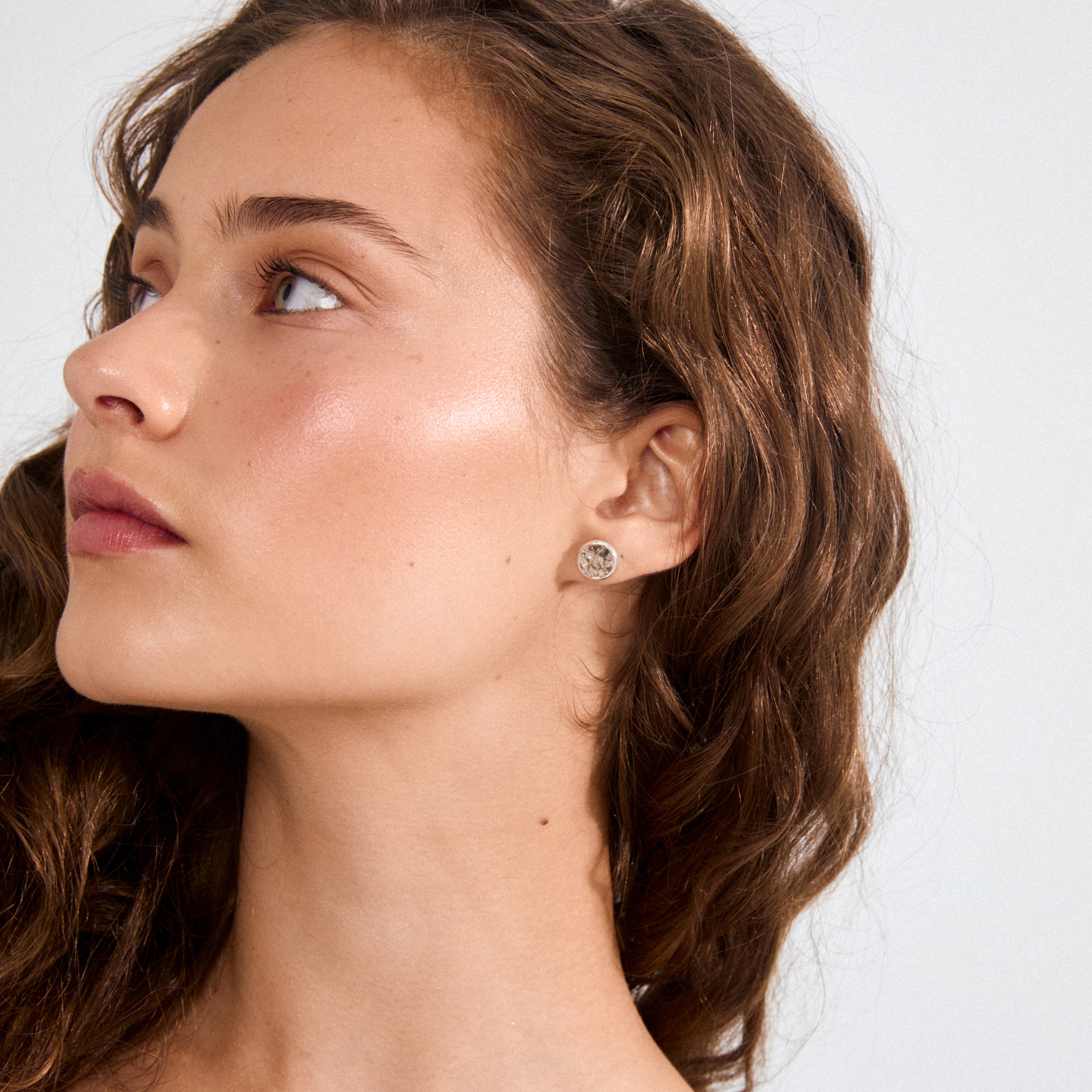 Young woman wearing a JOSEFINE earring, silver-plated with a rugged grey stone, showcasing a blend of bold texture and sleek finish.