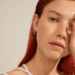 ELANOR rustic texture gold-plated hoop earrings, worn by a red-haired woman, showcasing their organic design and shiny finish, embodying Pilgrim's Scandinavian style.