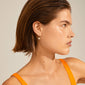 Profile of a woman wearing Pilgrim's ELINE pearl hoop earrings, gold-plated, featuring a shiny white pearl for an elegant and stylish look.