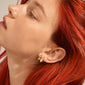 EDWINA chunky huggie hoop earrings, gold-plated, showcased on a woman with red hair, highlighting their chic, curved design and vintage-inspired elegance.