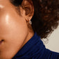 Close-up of a woman's ear adorned with Elise rose gold-plated oval link crystal earrings, showcasing edgy links and shiny Preciosa crystals.
