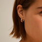 Close-up of a woman's ear wearing EFIA huggie hoop earrings, rose gold-plated, with engraved starry details, showcasing Pilgrim's blend of timeless and trendy design.