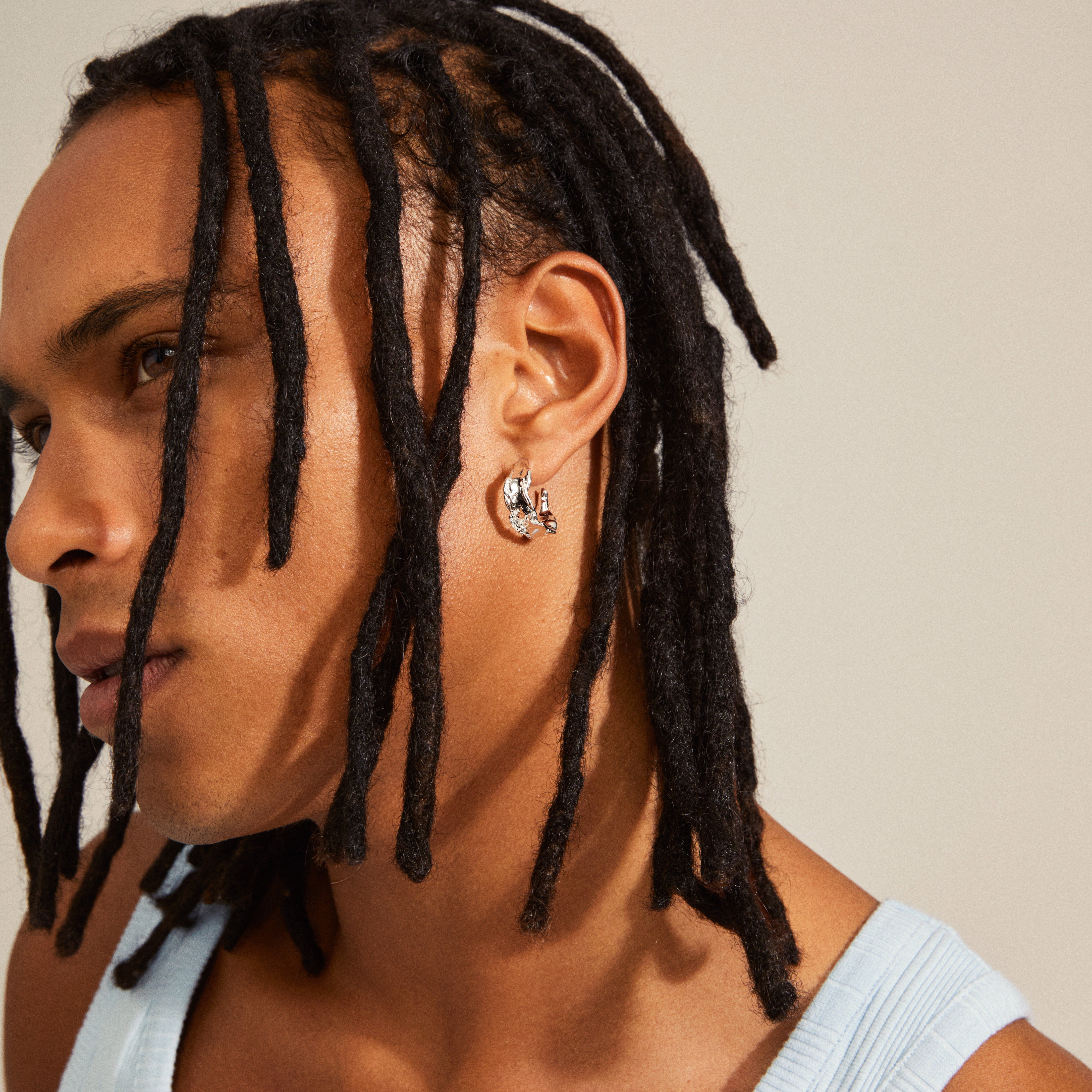 Silver-plated ELARA hoop earring, shaped with organic, handcrafted design, worn by a person with dreadlocks, embodying simple beauty and natural elegance.