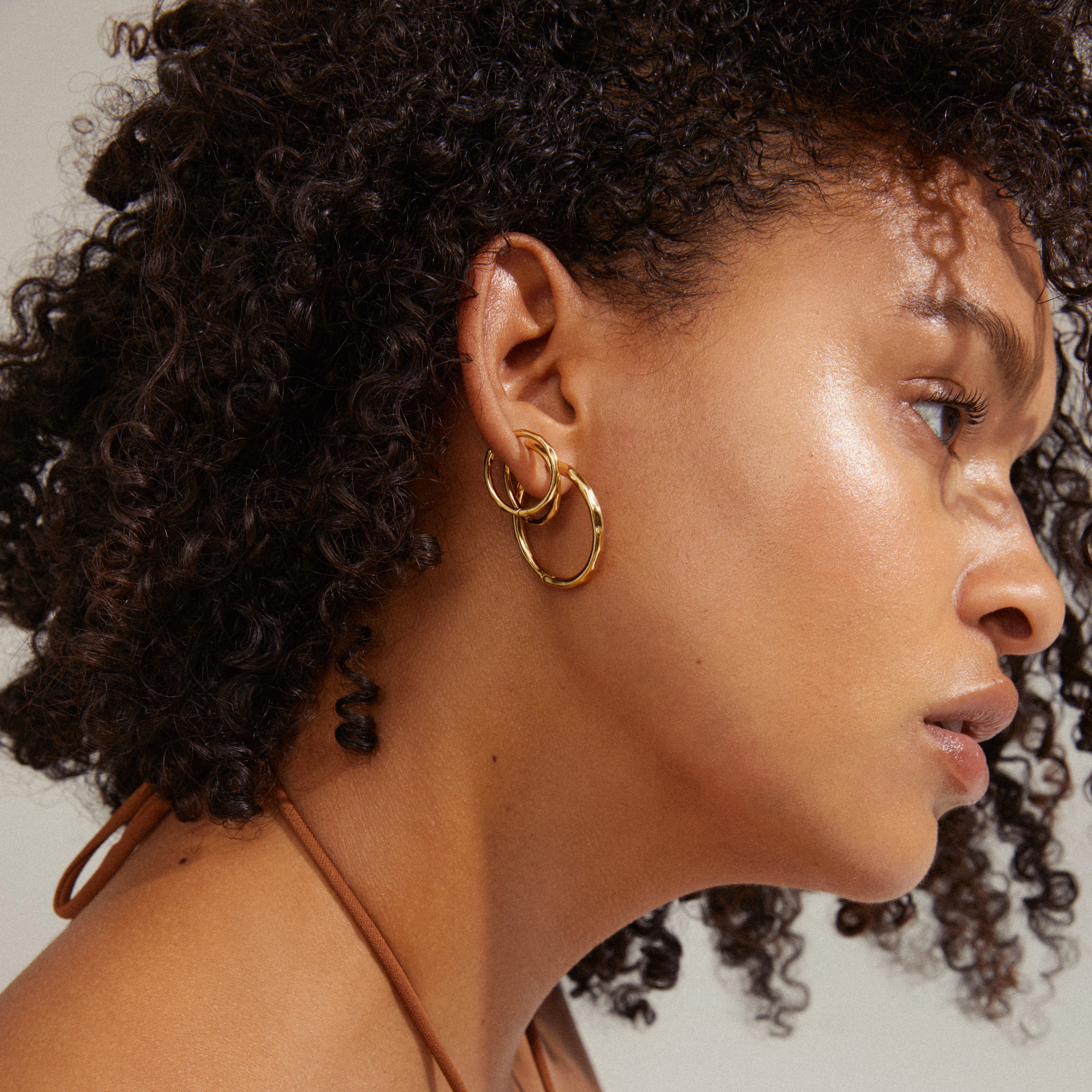 Woman wearing Pilgrim's EVE hoop earrings 2-in-1 set, gold-plated, showcasing elegant, versatile design for a stylish, curated ear look.