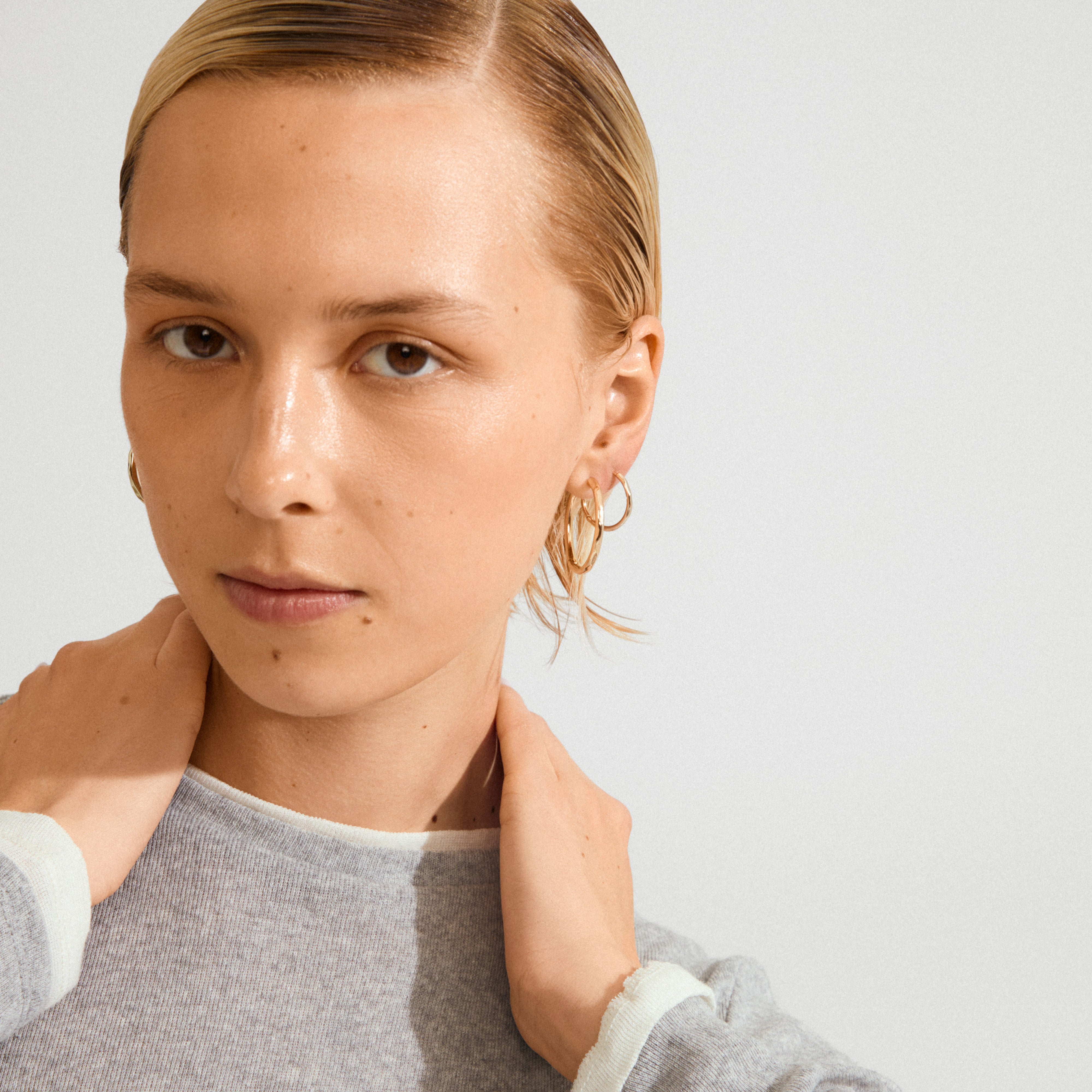 Young person wearing Pilgrim's EVE hoop earrings 2-in-1 gold-plated set, showcasing a stylish ear curation with several thin gold hoops.