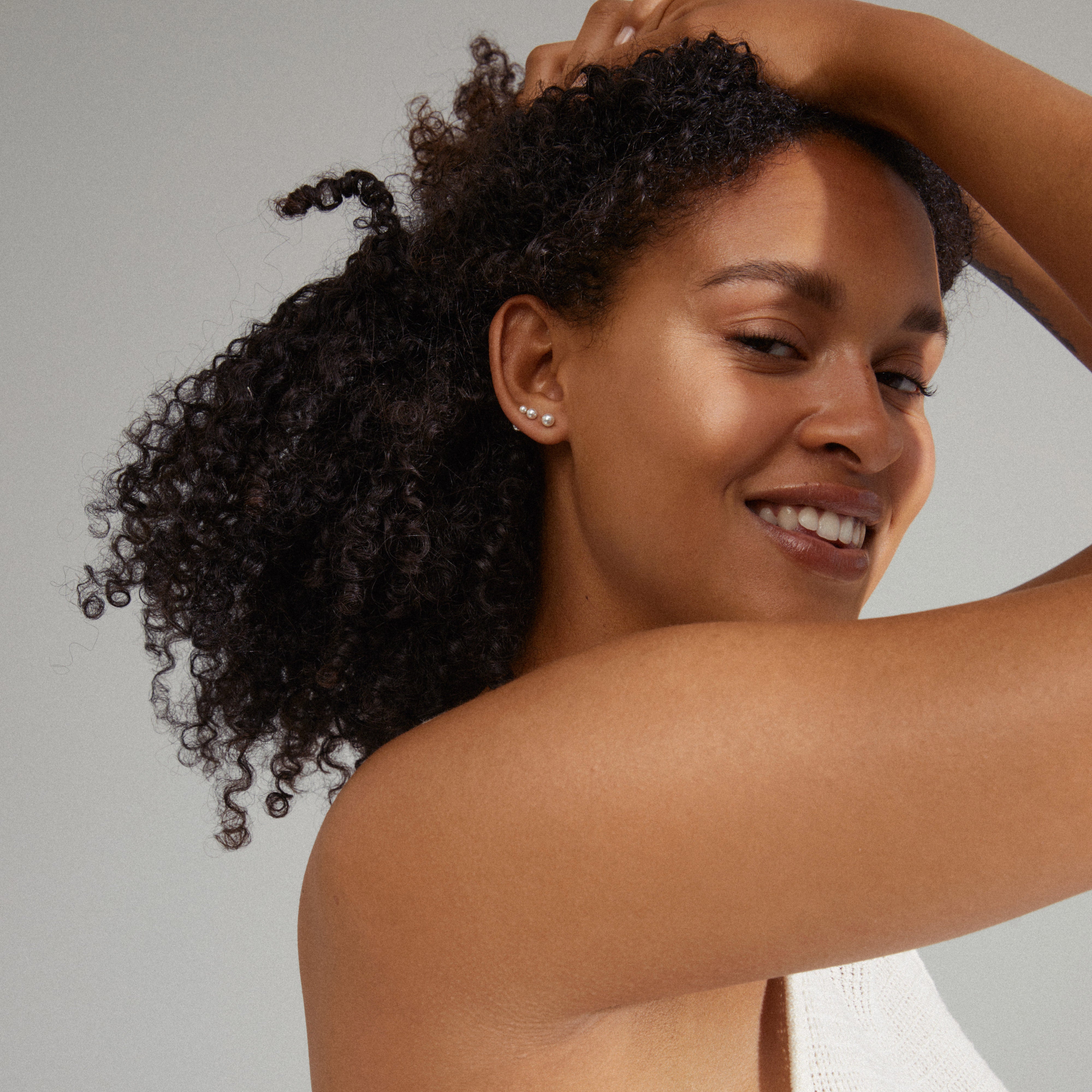ELISA pearl earrings 3-in-1 set showcased by a smiling woman, highlighting their elegance and versatility for a trendy, curated ear look.