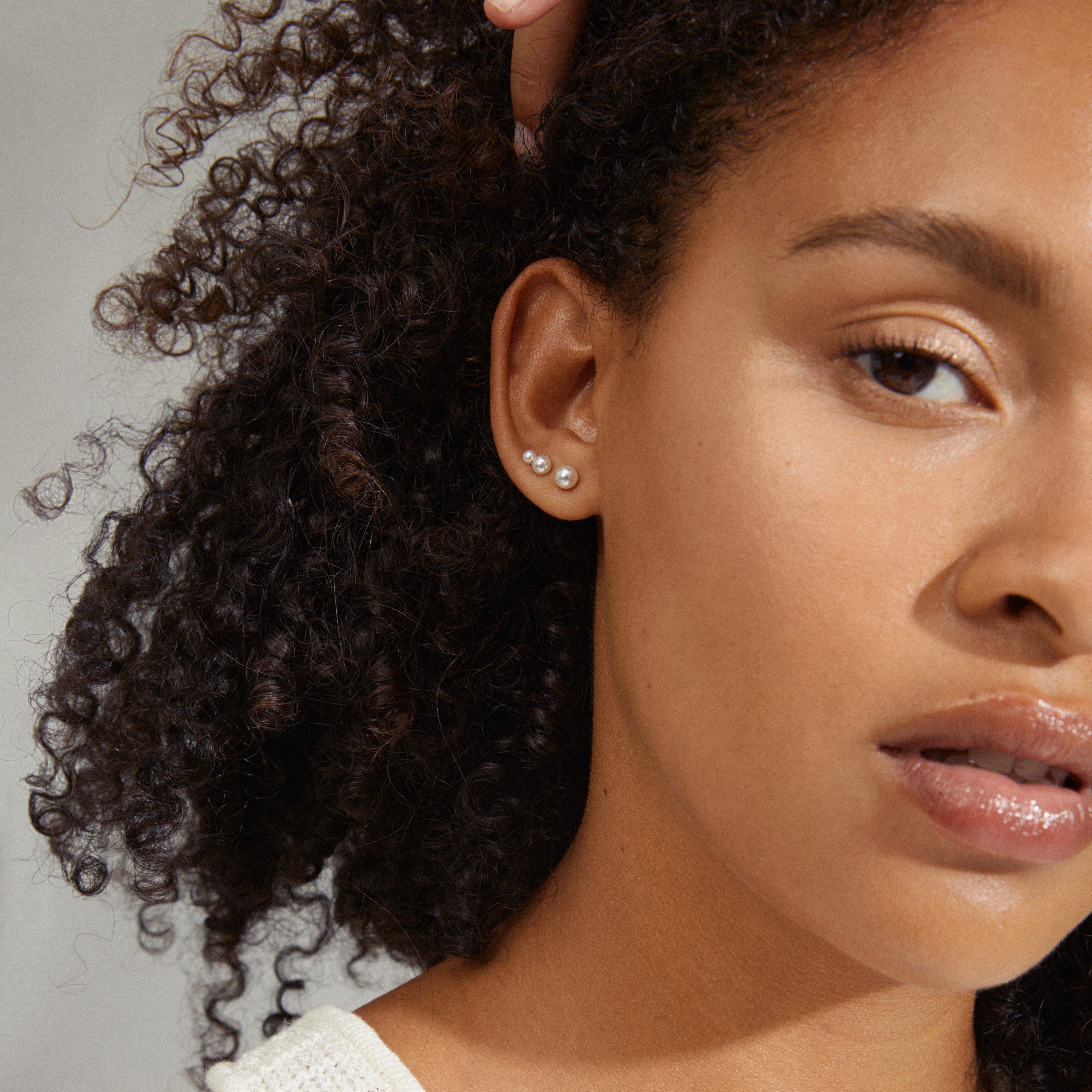 ELISA pearl earrings 3-in-1 set showcased on a woman with curly hair, highlighting the elegant silver-plated design and smooth pearls for a sophisticated look.