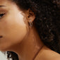 Close-up of a woman wearing Pilgrim's silver-plated ETTY crystal earrings, showcasing their elegant, fashion-forward design with sparkling Preciosa crystals.