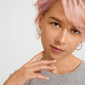 Young person with pastel-pink hair wearing Pilgrim's EVE hoop earrings 2-in-1 set, showcasing a minimalist style with silver-plated hoops for a personalized look.