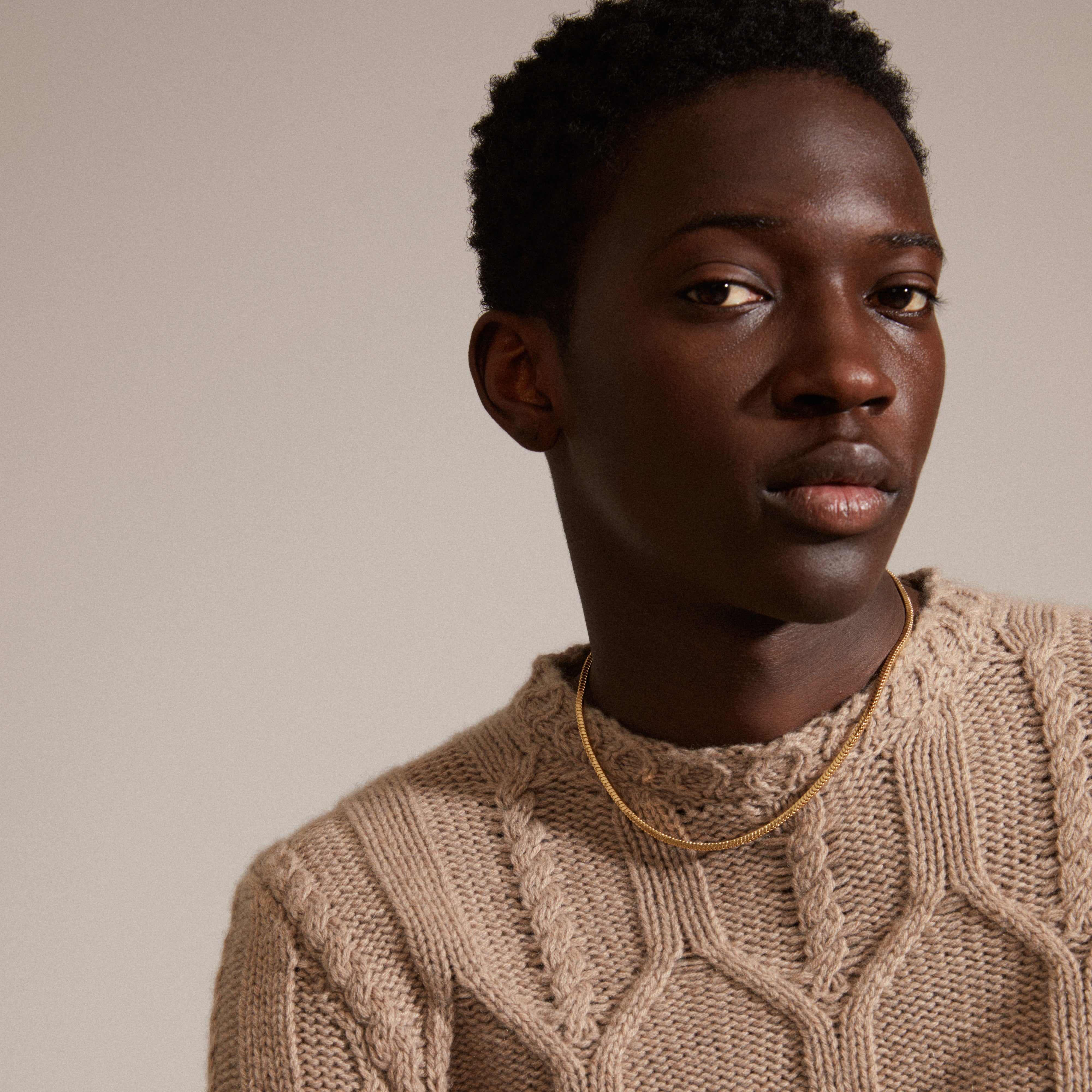 Man wearing a sweater showcasing the DOMINIQUE necklace gold-plated, a square snake chain design from Pilgrim's collection, emphasizing simplicity and timeless elegance.