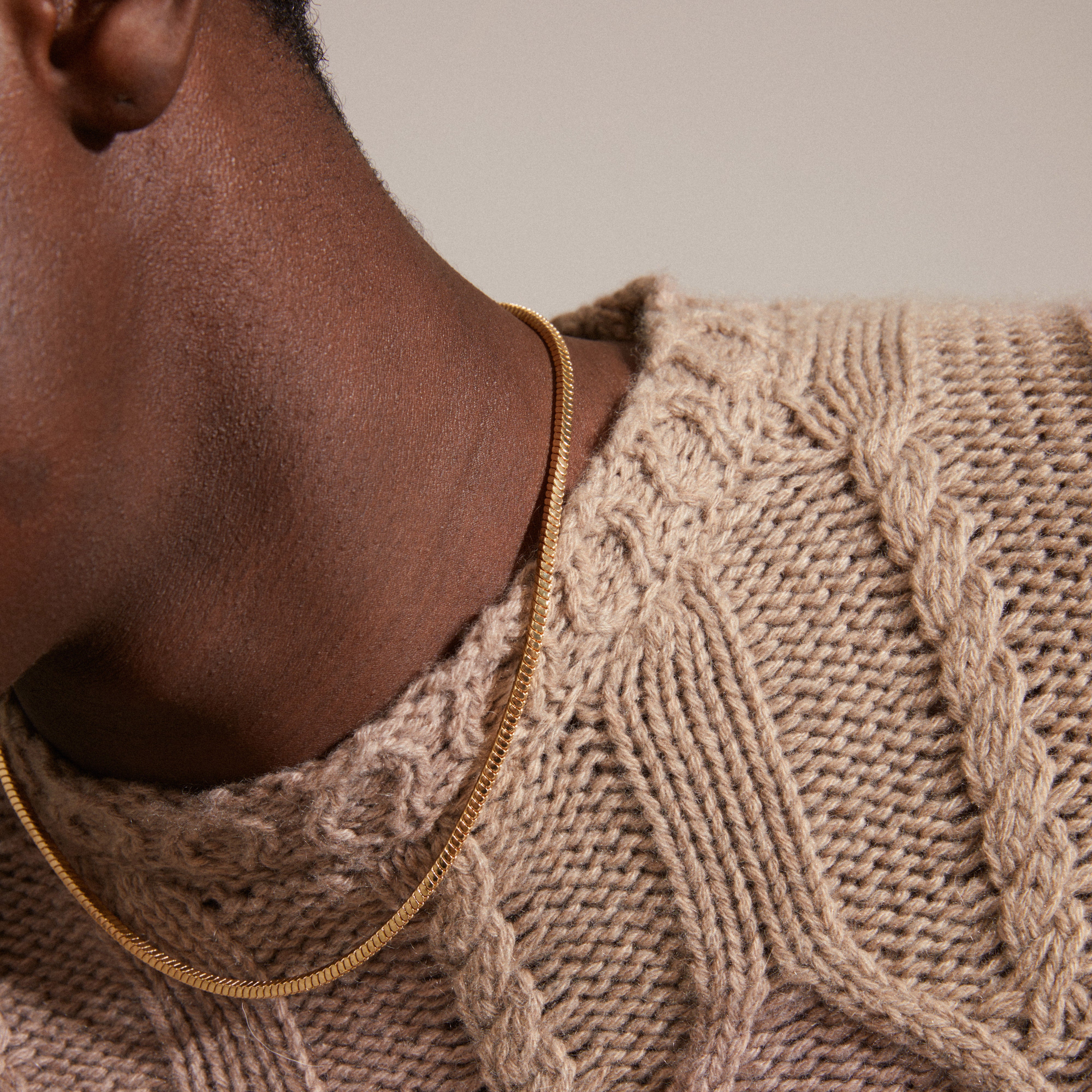DOMINIQUE necklace gold-plated showcased on a person wearing a sweater, highlighting the elegant square snake chain design, a standout piece from Pilgrim's collection.