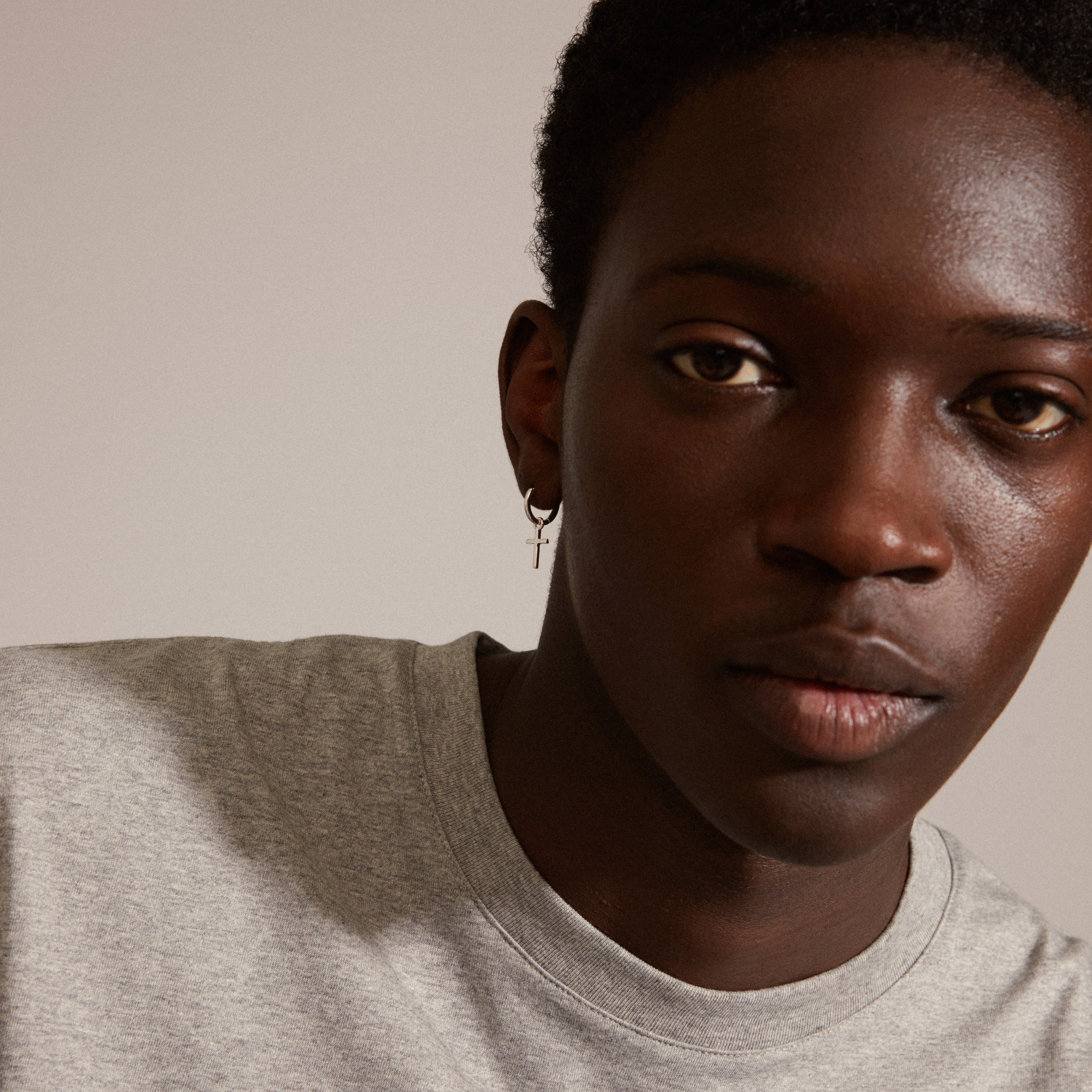 DAISY cross hoops silver-plated earrings with removable cross pendant, showcased in a close-up portrait. Stylish and simple design, emphasizing a classic and Nordic aesthetic.