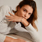 Woman lying down, showcasing the DOMINIQUE bracelet silver-plated from Pilgrim, featuring a square snake design and shiny surfaces for a stylish, genderless look.
