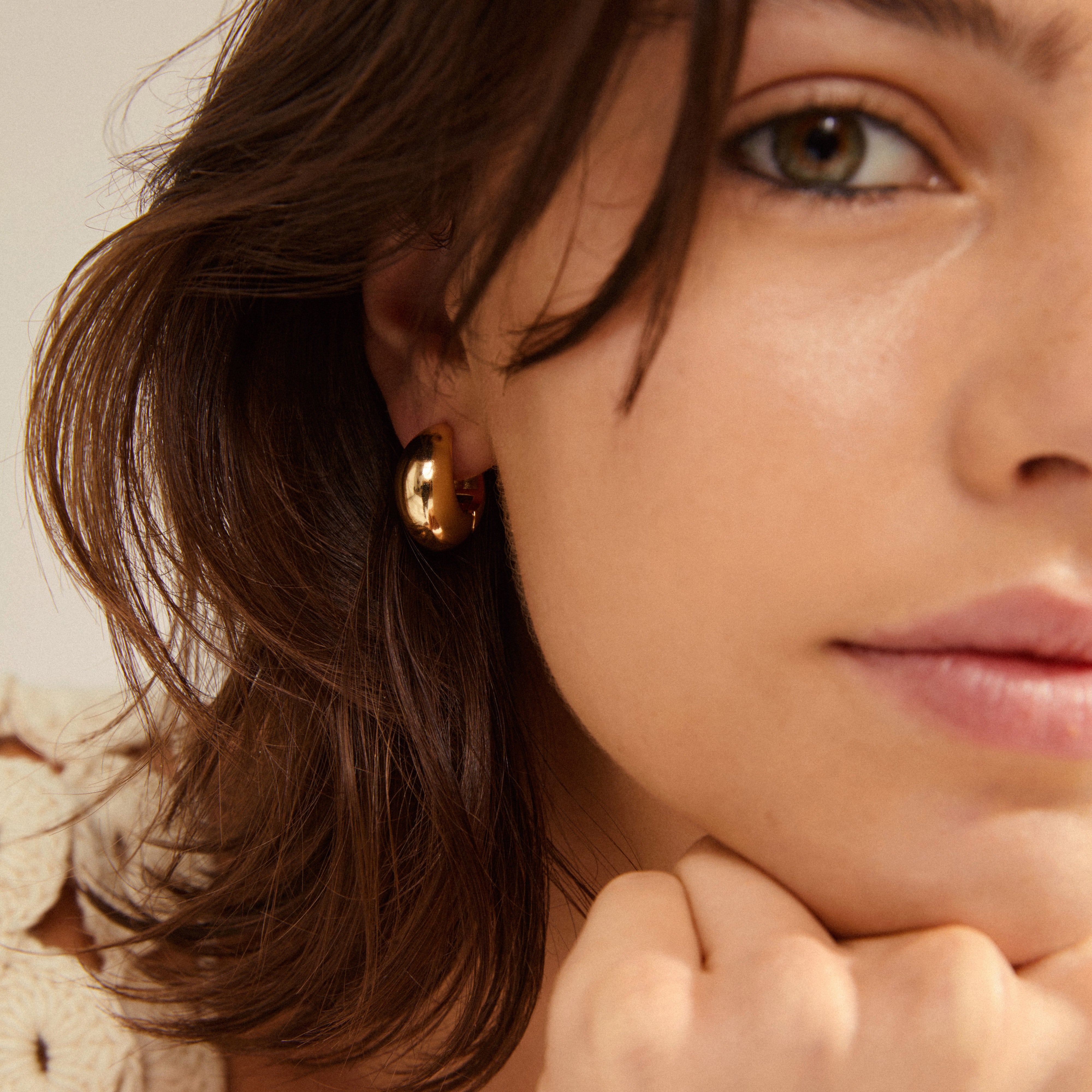 IOANNA chunky hoops gold-plated earrings, featuring a wide, shiny design on a woman's ear, adding a stylish and elegant Nordic touch.