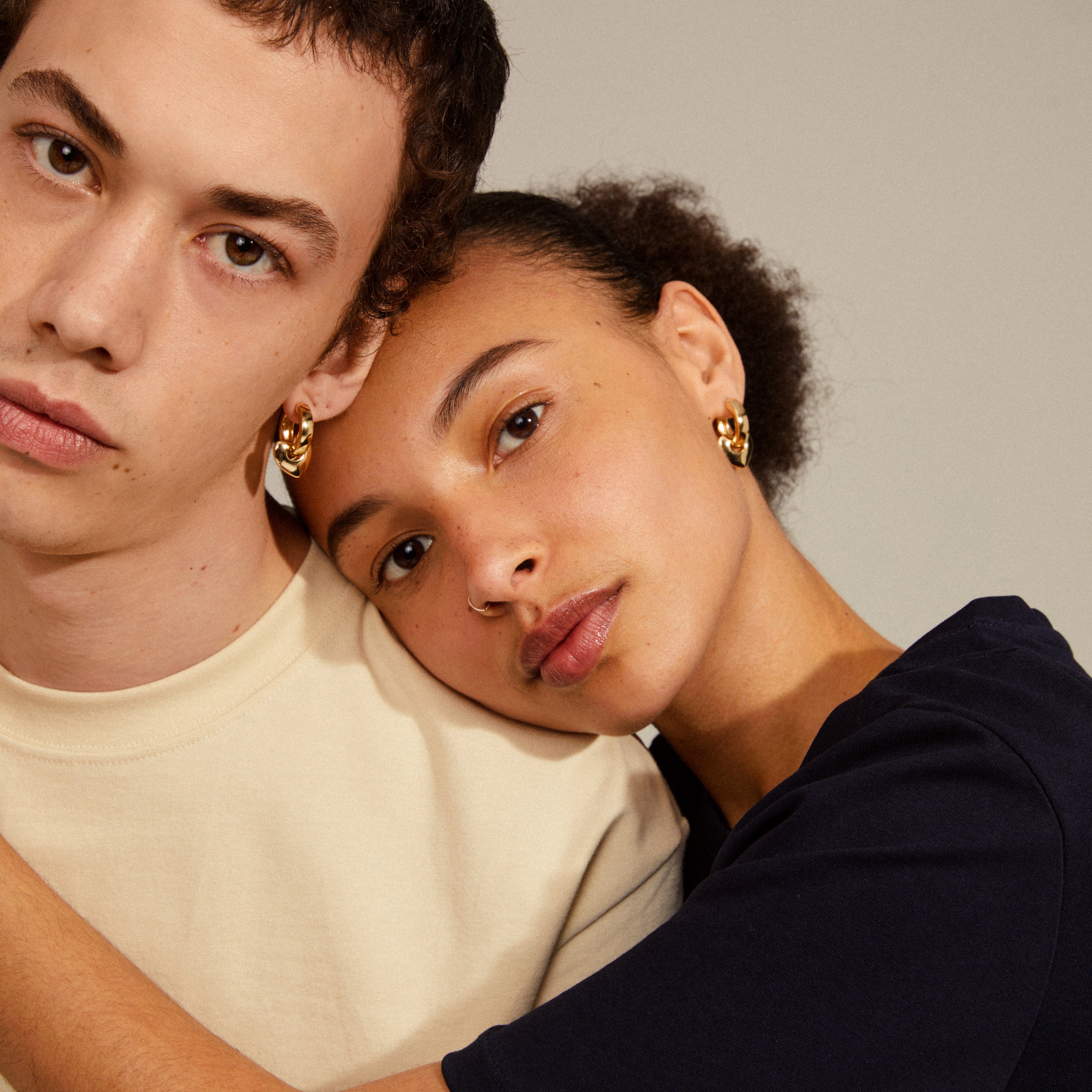 IOKASTE chunky hoops gold-plated earrings featuring removable heart pendants, worn by a woman resting on a man's shoulder, highlighting their elegant design and versatility.