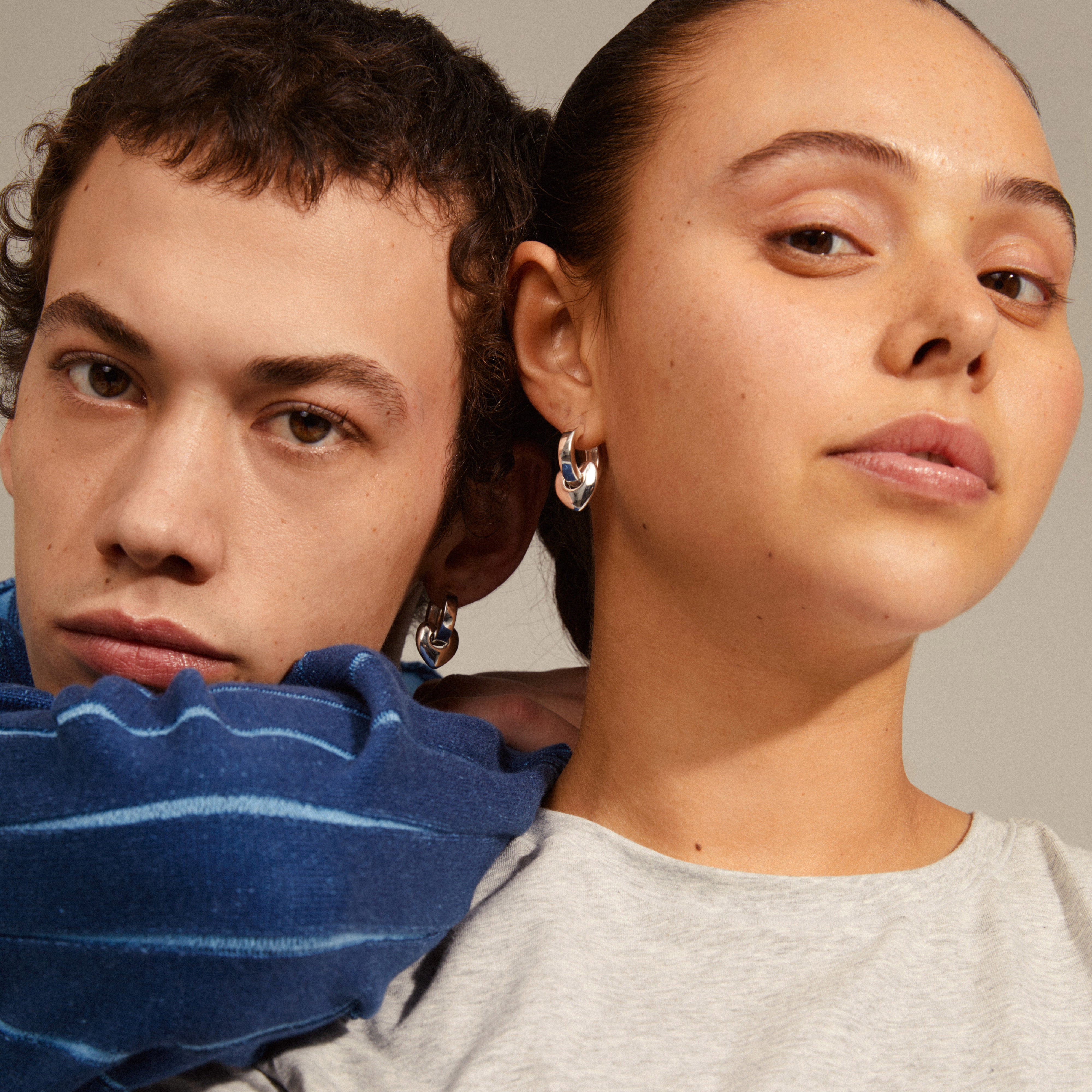 IOKASTE chunky hoops silver-plated earrings with detachable heart pendants, showcased by a man and woman.